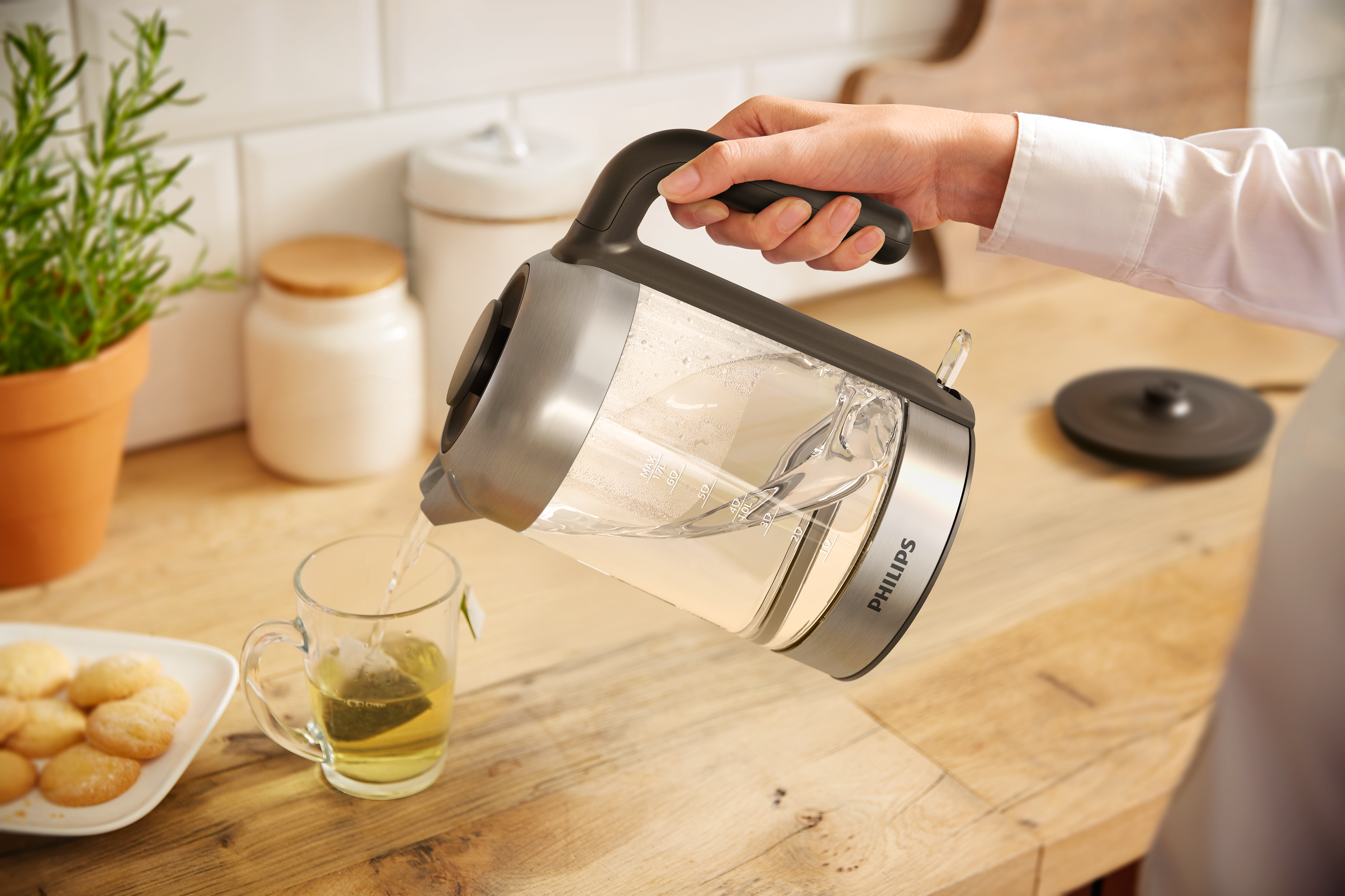 Una persona vierte agua caliente de una tetera en una taza con una bolsita de té.