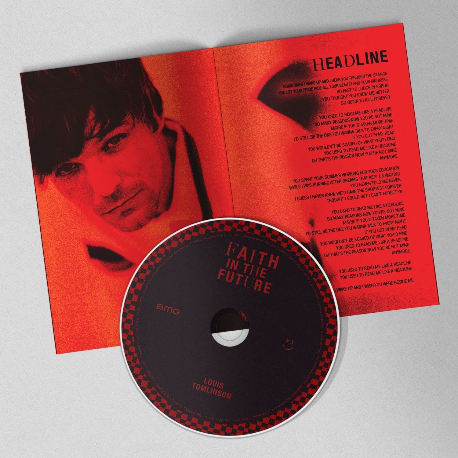 Il CD e il testo dell'album di Louis Tomlinson. Lo sfondo è rosso con la foto dell'artista.