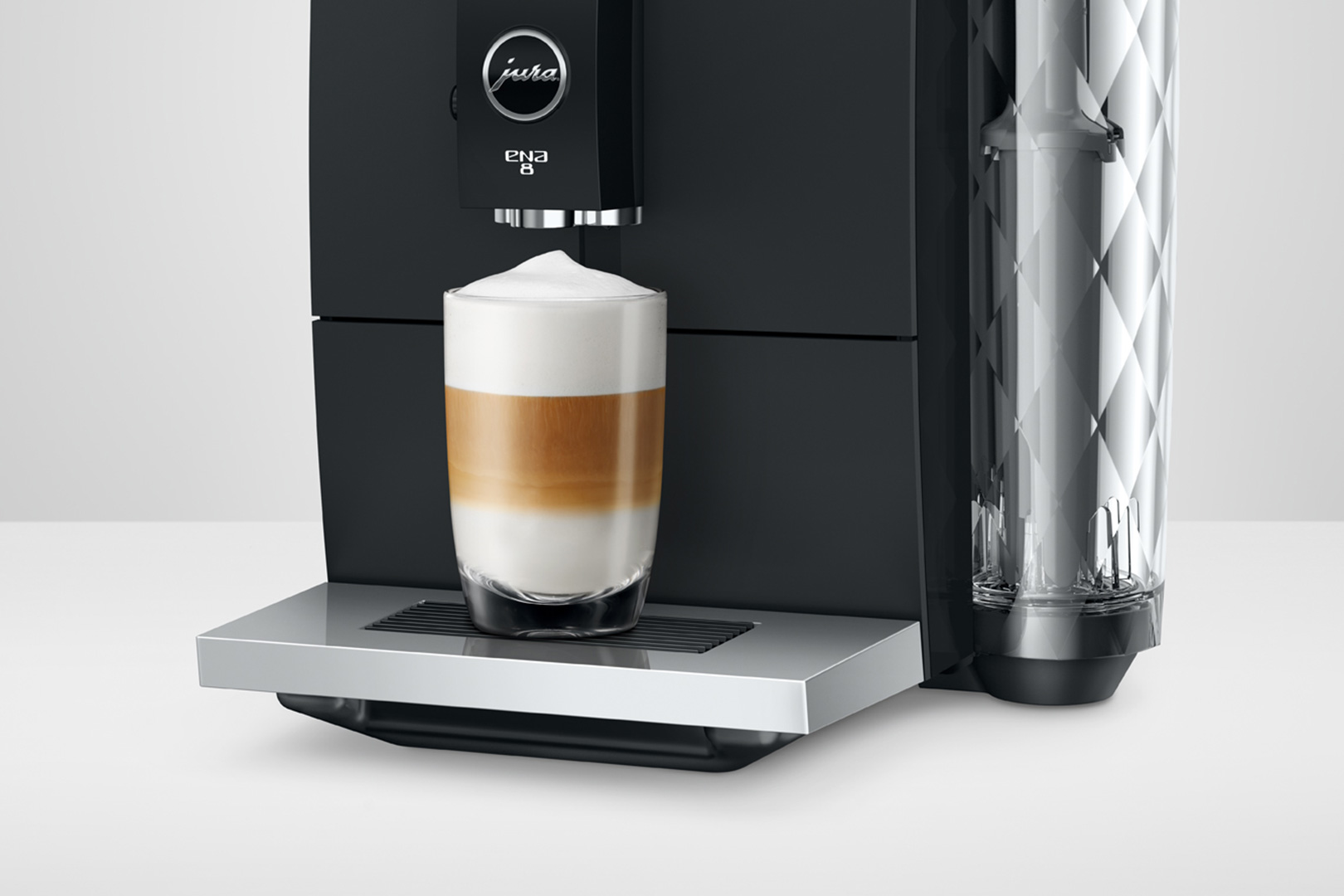 Macchina da caffè Jura ENA 8 con un bicchiere di latte macchiato a strati.