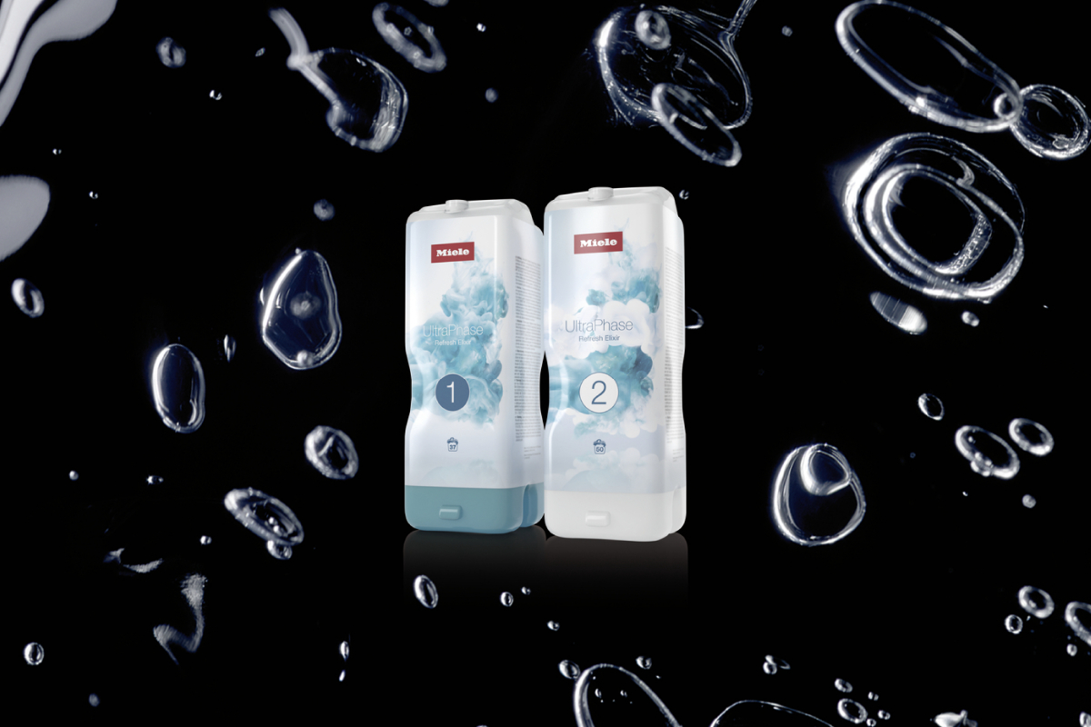 Zwei Miele UltraPhase Waschmittelflaschen, beschriftet mit 1 und 2, stehen vor einem schwarzen Hintergrund mit Wasserblasen.