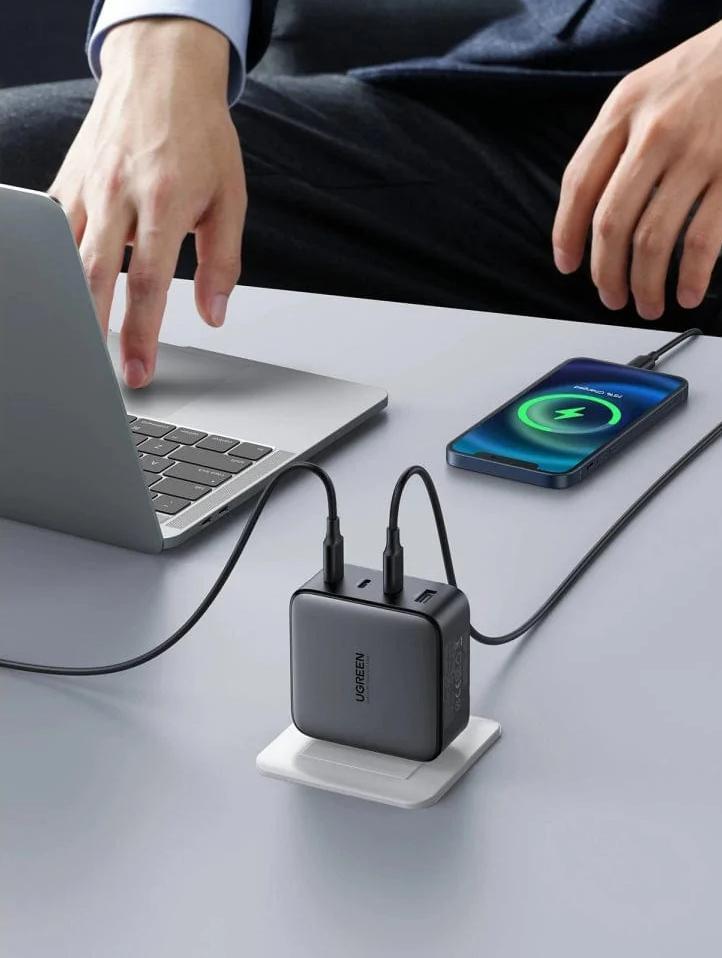 Une personne utilise un ordinateur portable, charge un téléphone et une station de charge.