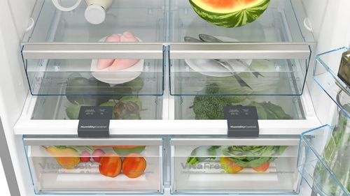 Interior de un refrigerador. Frutas y verduras en cajones. Comida en estantes.