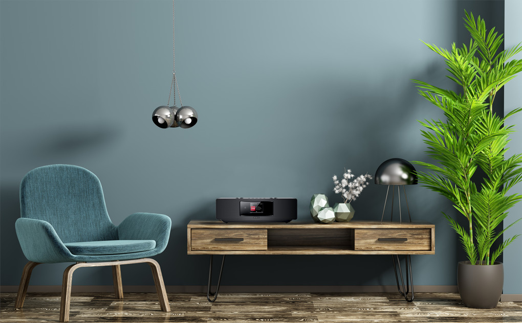 A living room setup with a blue chair, table with decor, and a plant, on a blue wall.