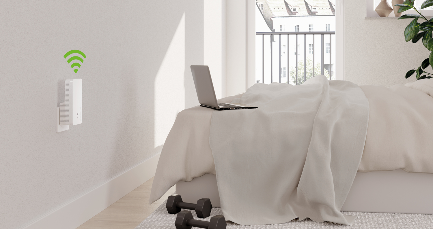 Slaapkamer met laptop op bed, dumbbells en een aan de muur gemonteerd apparaat met Wi-Fi-symbool.