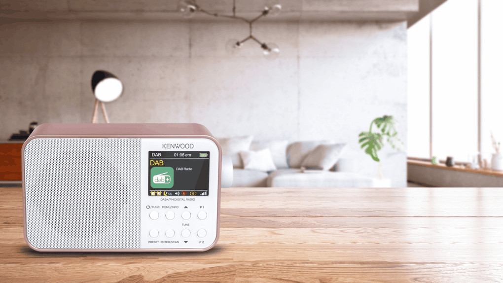 Pink digital radio on a wooden table, in a living room setting.