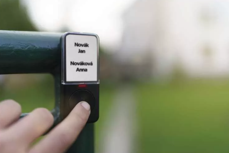 Egy személy keze megnyom egy gombot egy fekete névtáblán.
