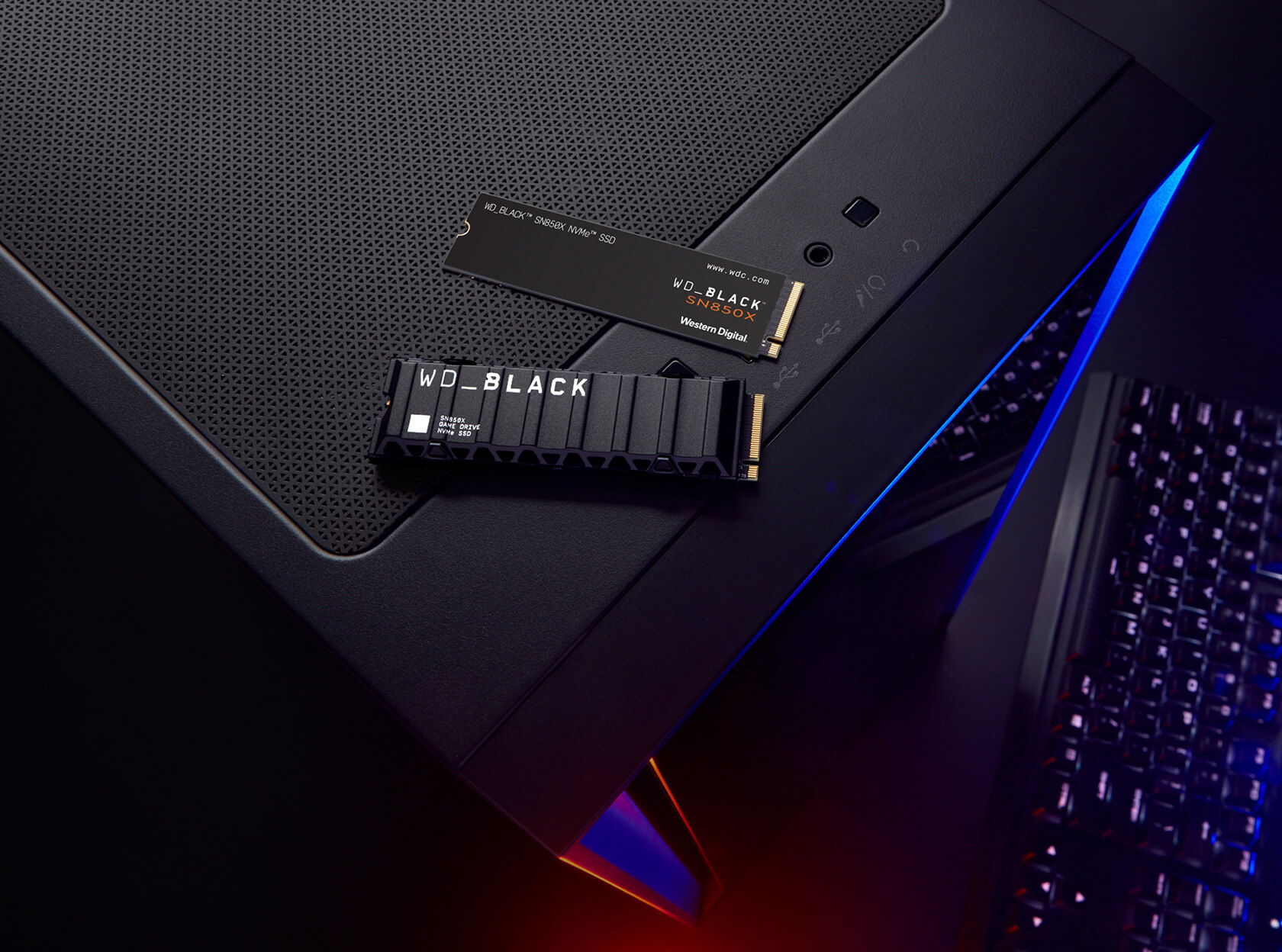 Schwarzes Computergehäuse mit zwei schwarzen WD_BLACK SSDs oben. Tastatur unten rechts.