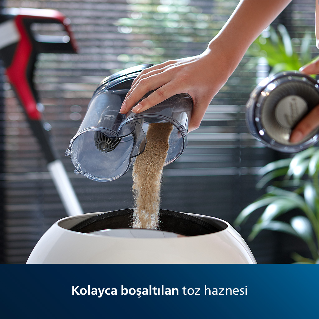 Bir kişi, elektrikli süpürgenin toz haznesini beyaz bir kaseye boşaltıyor. Arka plan: bitkiler.