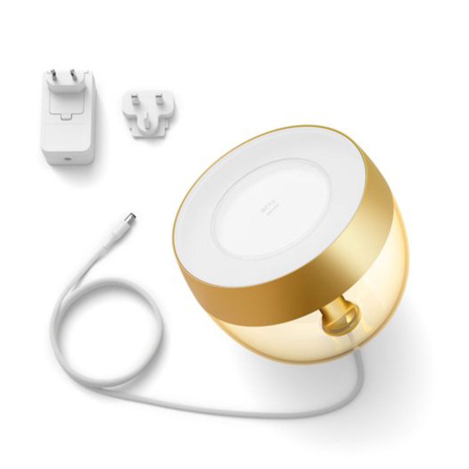 Una lampada oro e bianca con un adattatore di alimentazione, un adattatore per spina e un cavo USB su una superficie bianca.