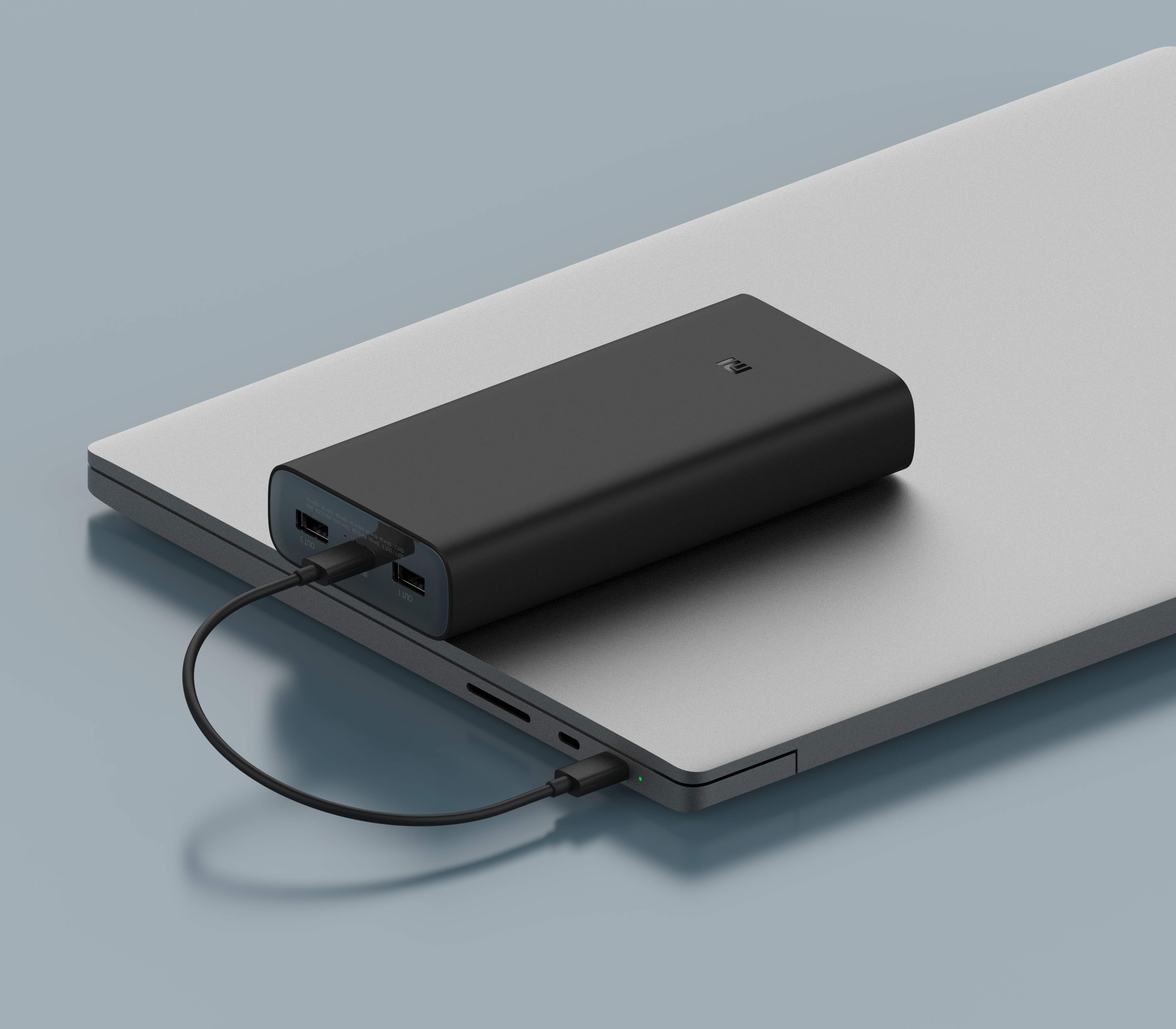 Un power bank nero è posizionato su un laptop argentato. Un cavo li collega.