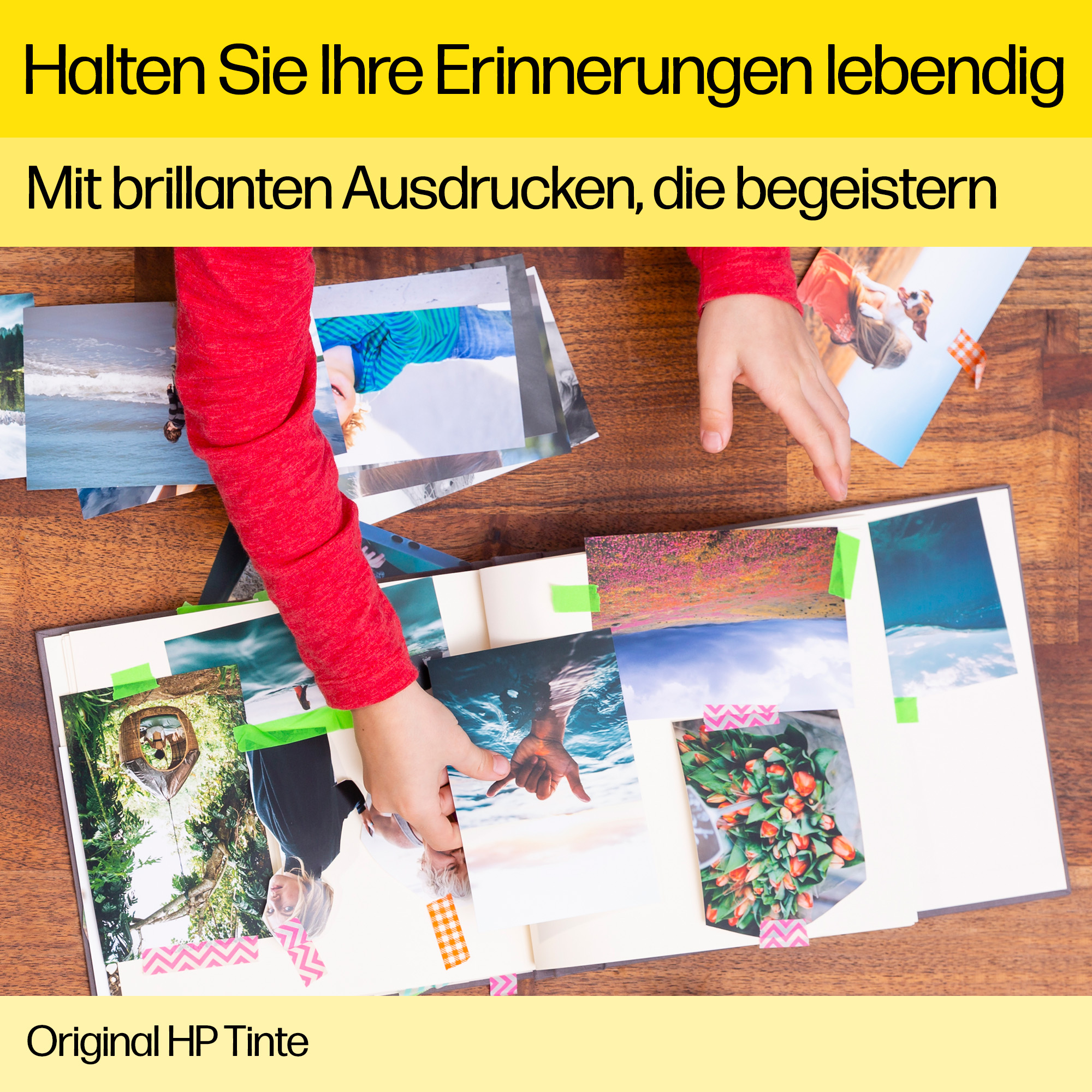 Die Hände eines Kindes ordnen Fotos in einem Album an. Die Fotos werden mit Klebeband gehalten.