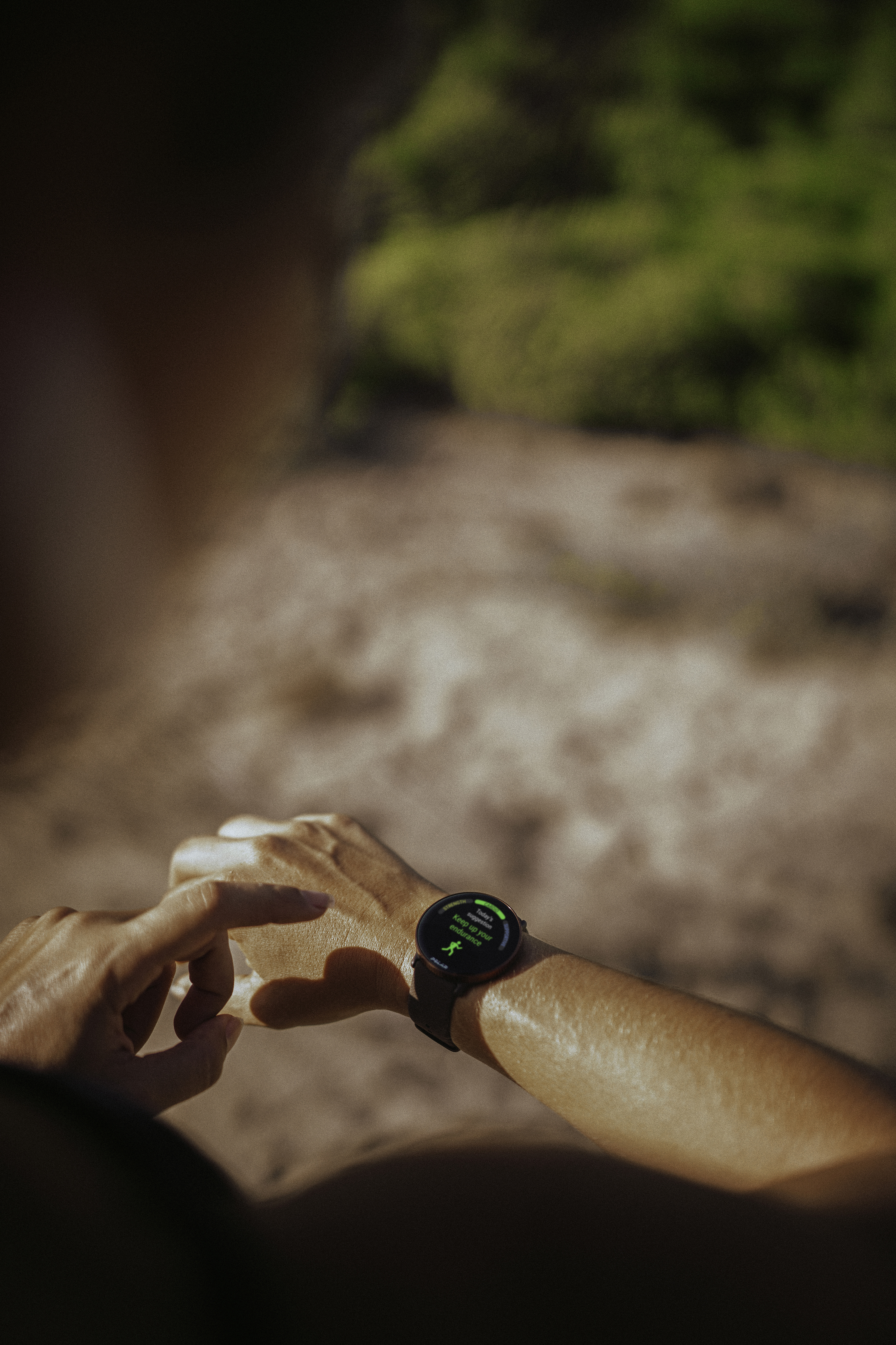 Persona revisando smartwatch mostrando métricas, al aire libre con fondo borroso.