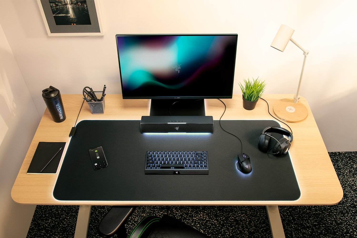Ein gut beleuchteter Schreibtisch mit technischen Geräten: Monitor, Tastatur, Maus und Kopfhörer.