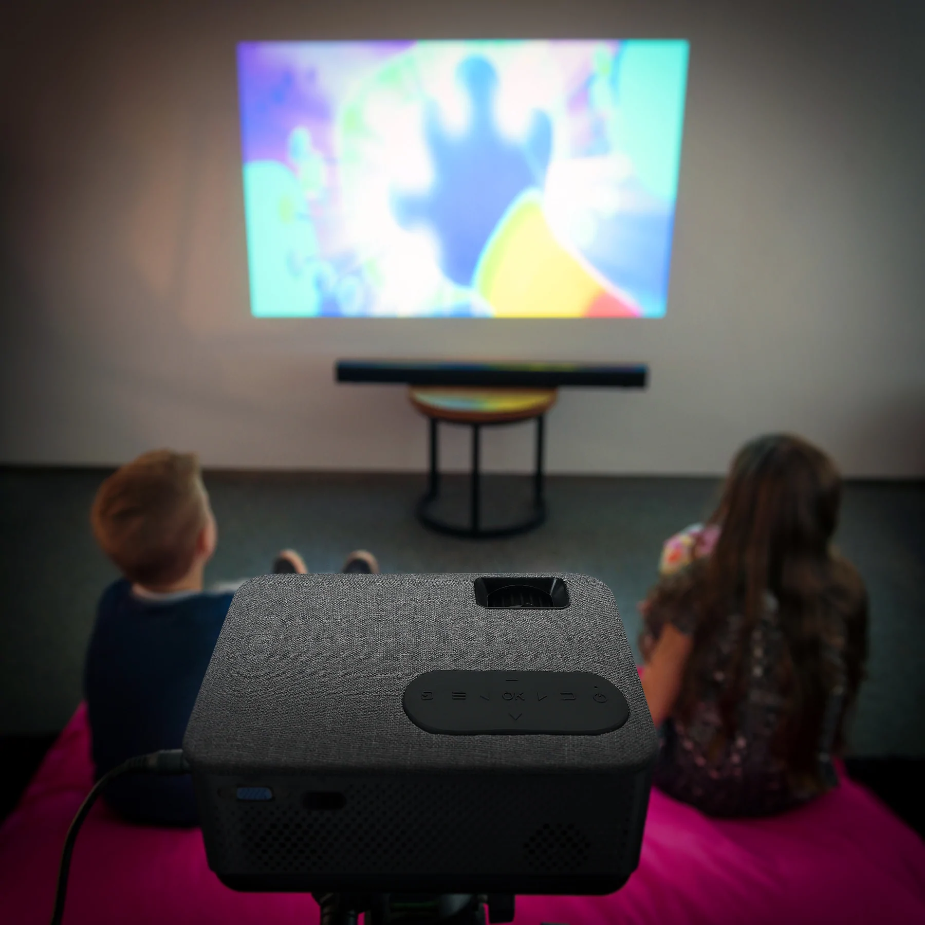Projecteur projetant une image colorée sur un mur. Deux enfants regardent.