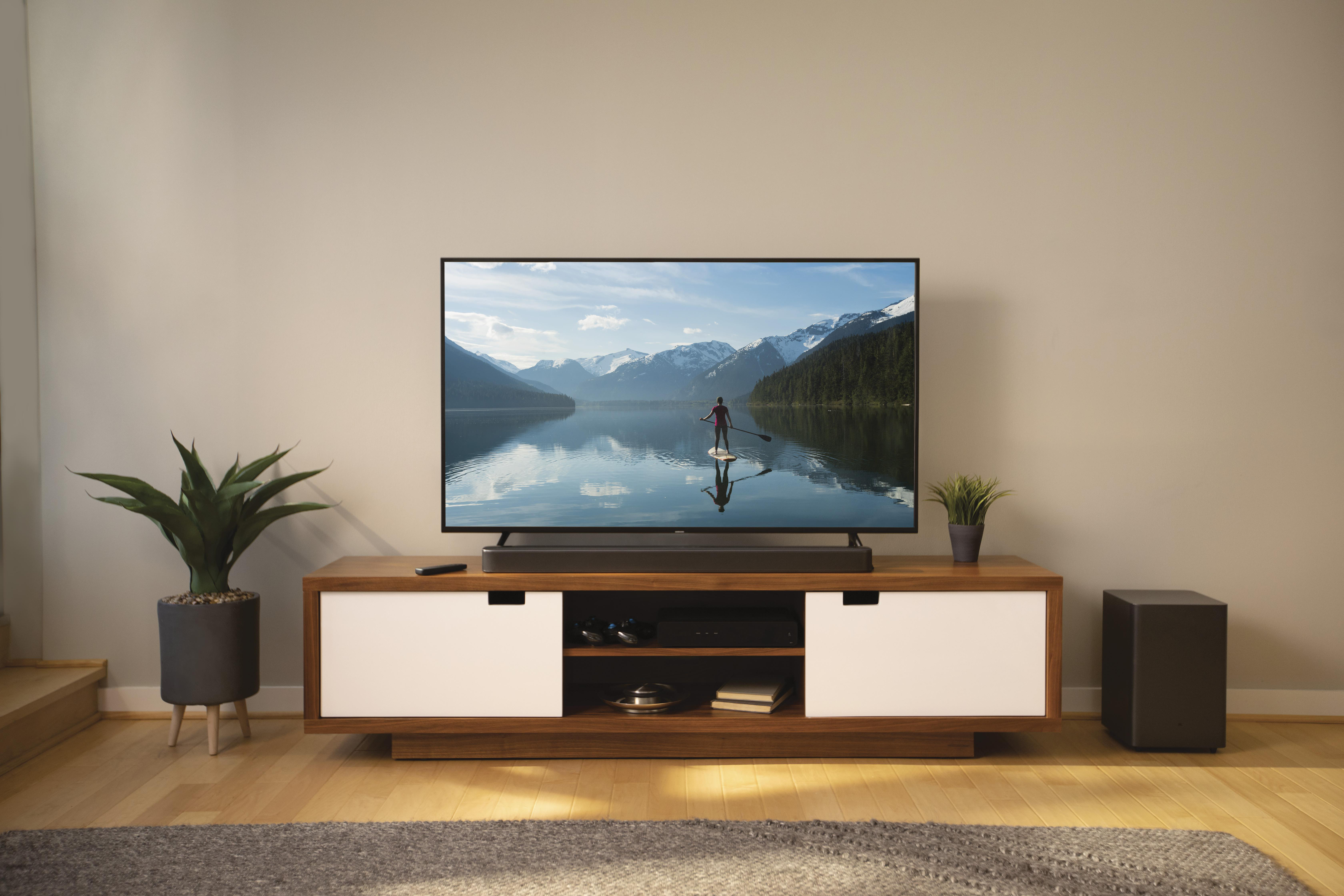 Ein modernes Wohnzimmer mit Fernseher, Soundbar und Schrank.