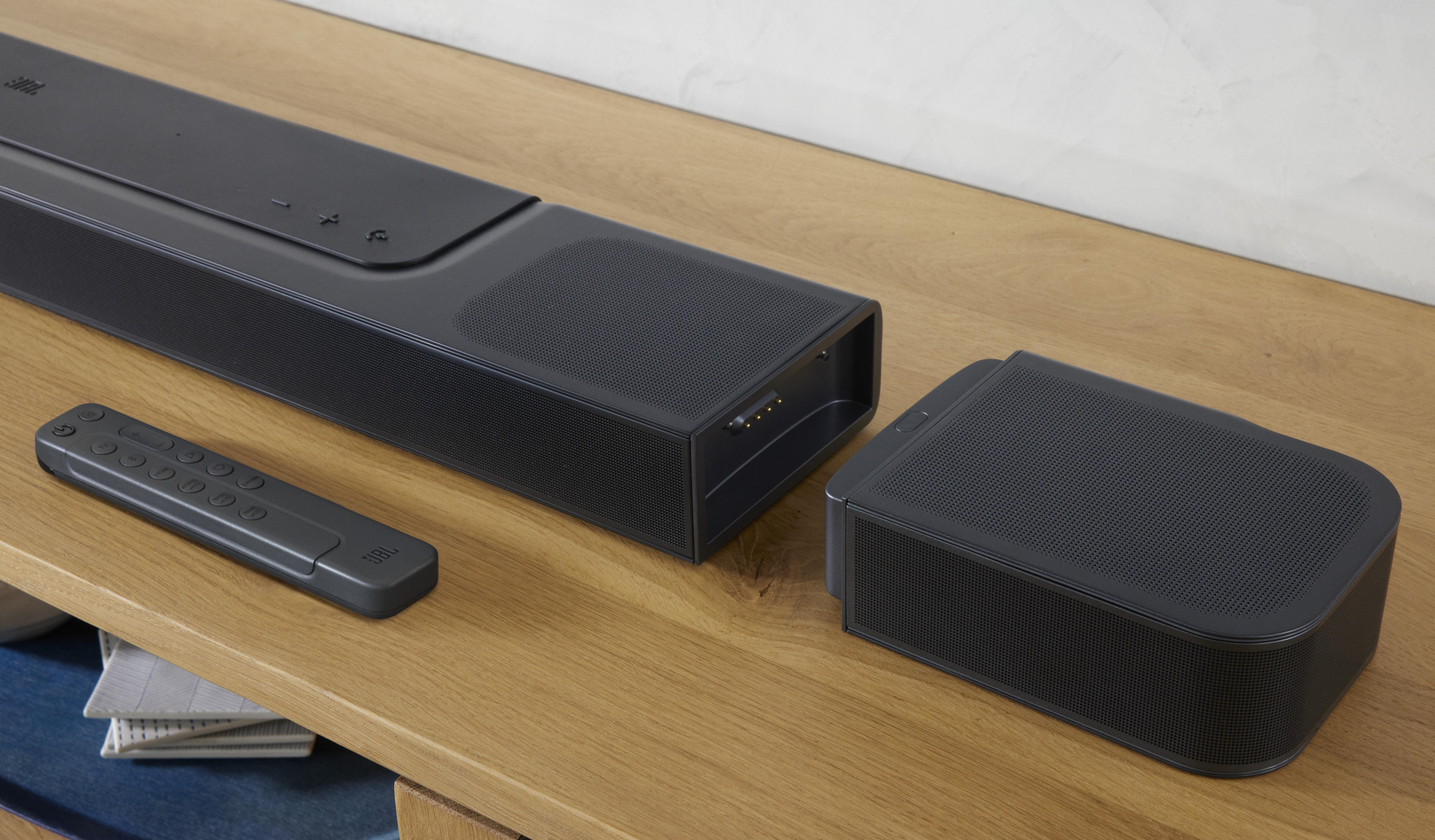 Schwarze JBL Soundbar mit Subwoofer und Fernbedienung auf Holzoberfläche.