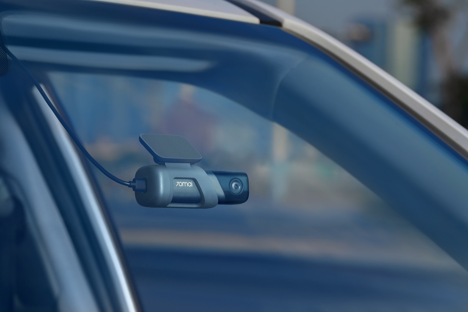 Egy autó szélvédője egy dashcam-mel. A kamera szürke és fekete.