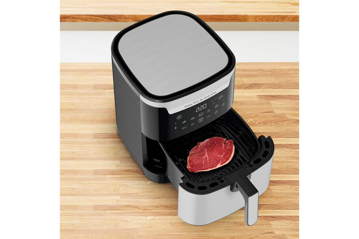 Levegősütő steakkel. Fekete-ezüst készülék fa felületen.