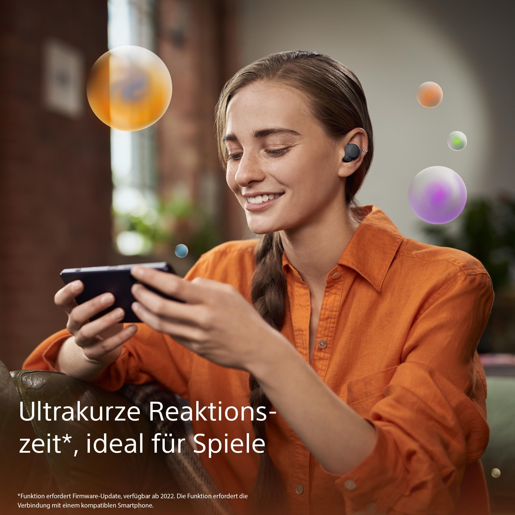 Lächelnde Frau hält ein Telefon, trägt Ohrhörer, mit bunten, schwebenden Kugeln.