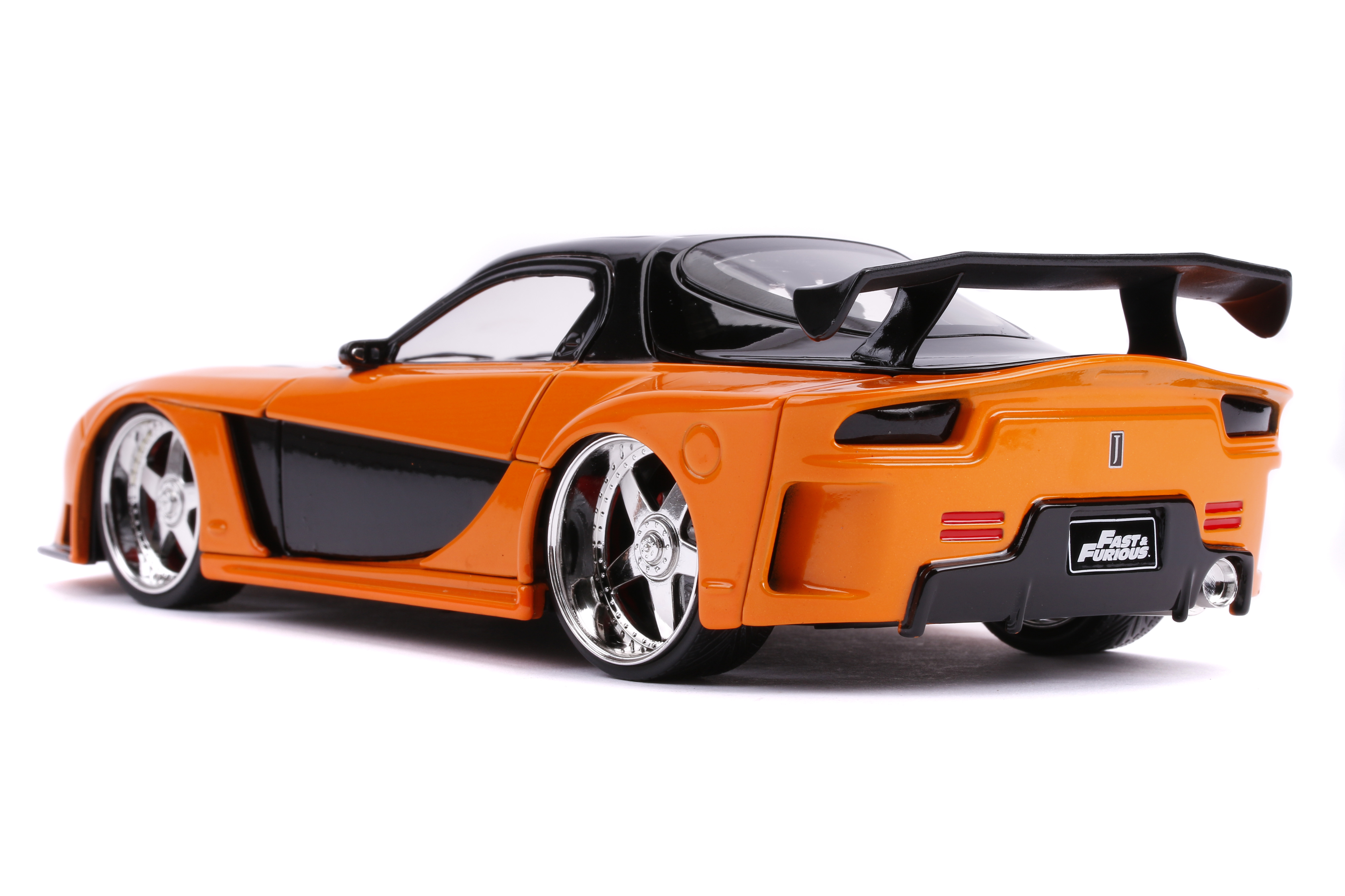 Ein orange-schwarzes Spielzeugauto mit Spoiler. Das Auto hat silberne Felgen und das Fast & Furious Logo.