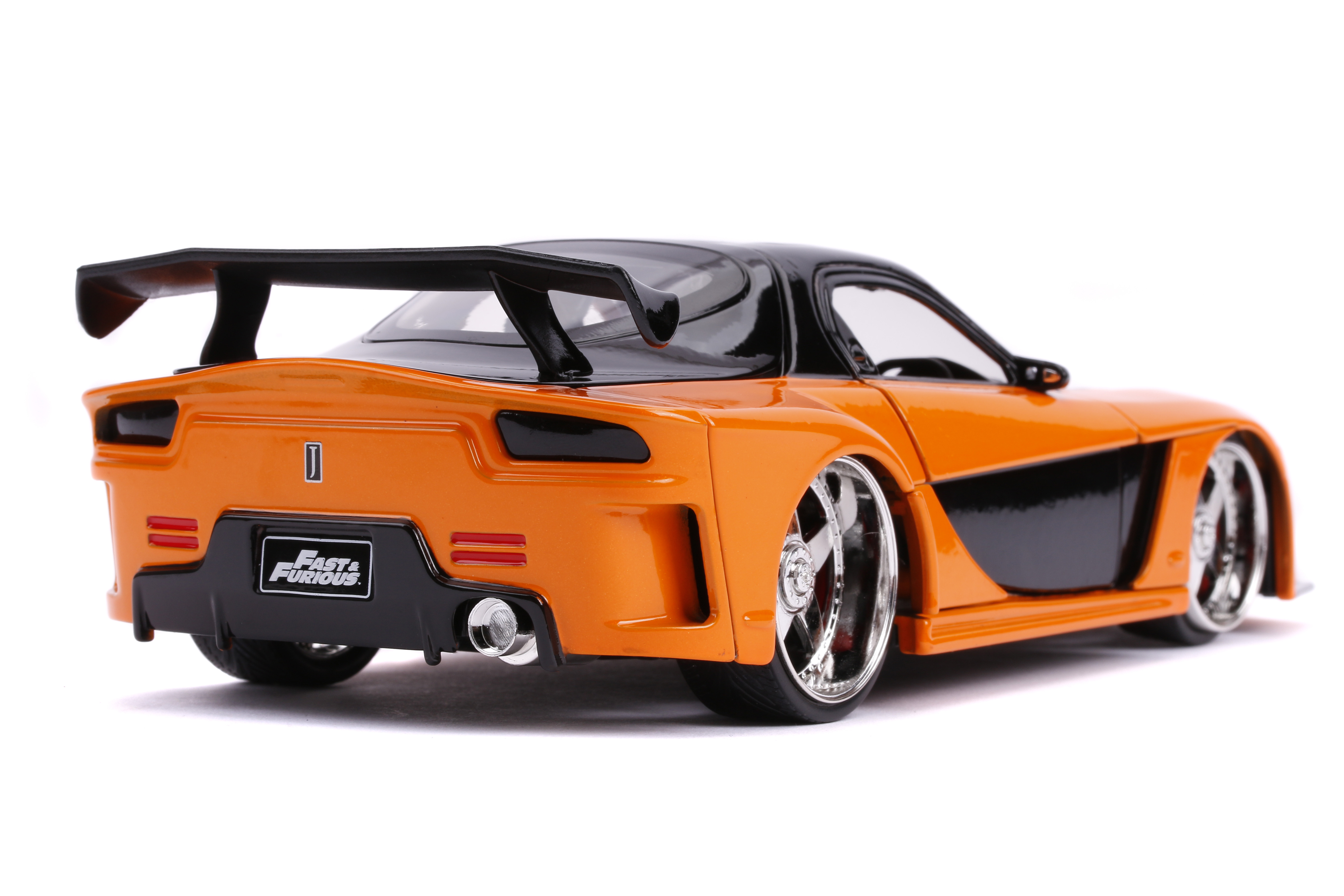Ein orange-schwarzes Spielzeugauto, ein Fast & Furious-Modell, mit Chromfelgen und großem Spoiler, vor weißem Hintergrund.
