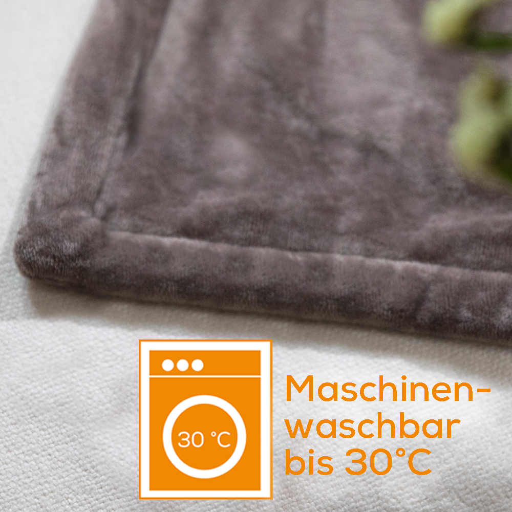 Primo piano di una coperta grigia con simbolo della lavatrice e testo: Lavabile in lavatrice fino a 30°C.