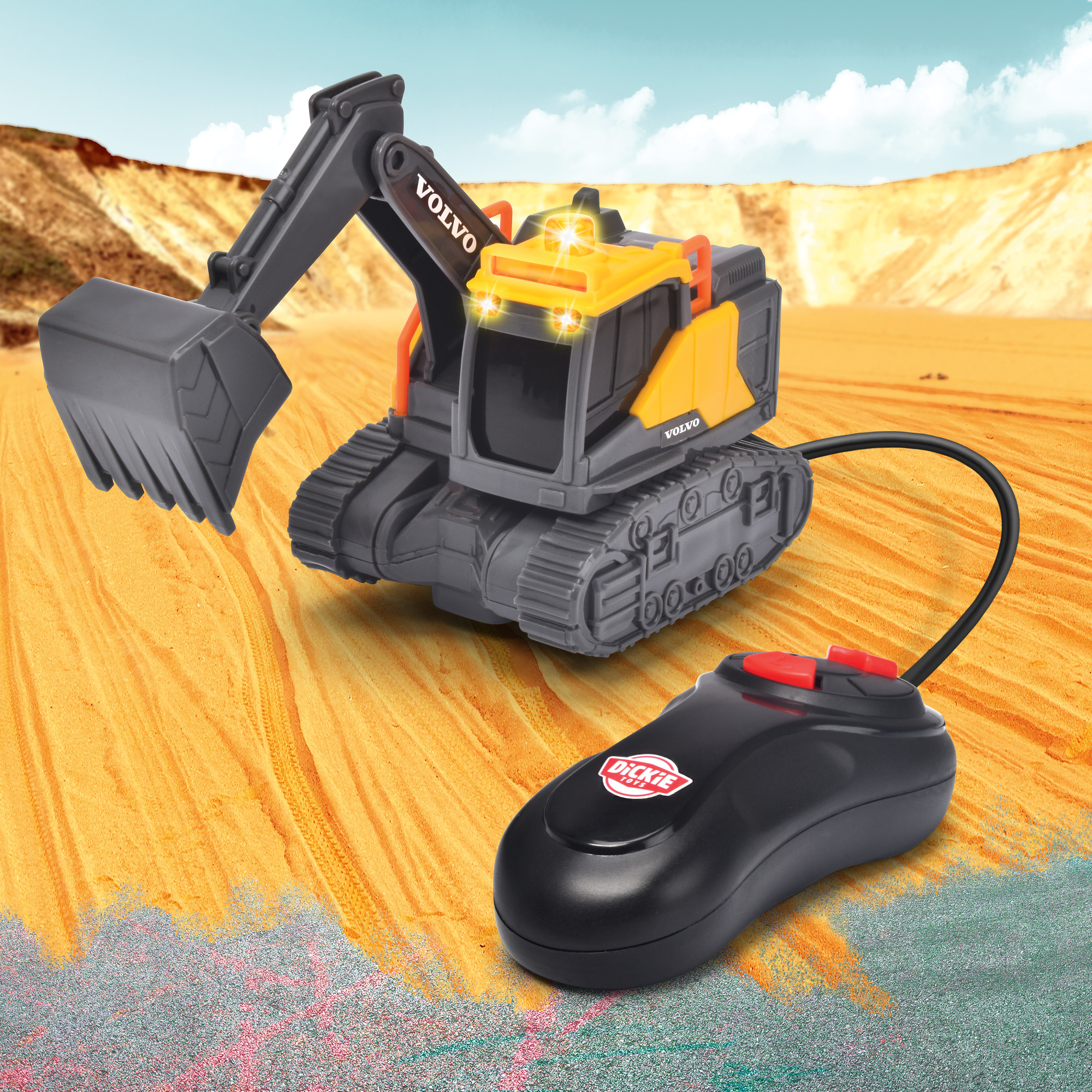 Ein Spielzeugbagger mit Fernbedienung auf Sand. Das Spielzeug ist gelb und schwarz.