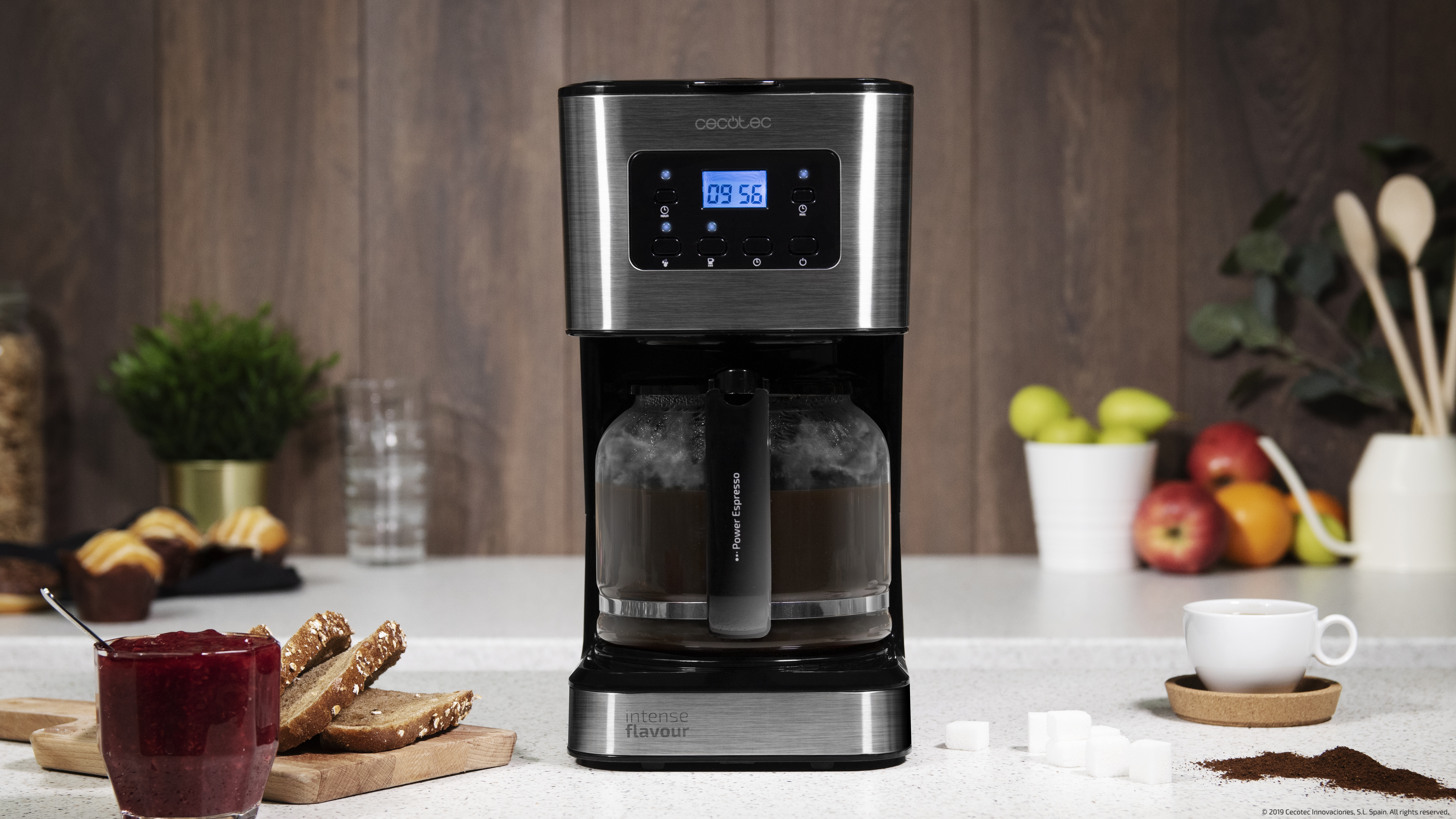 Una cafetera con pantalla digital, una jarra de cristal con café y un mostrador de cocina.