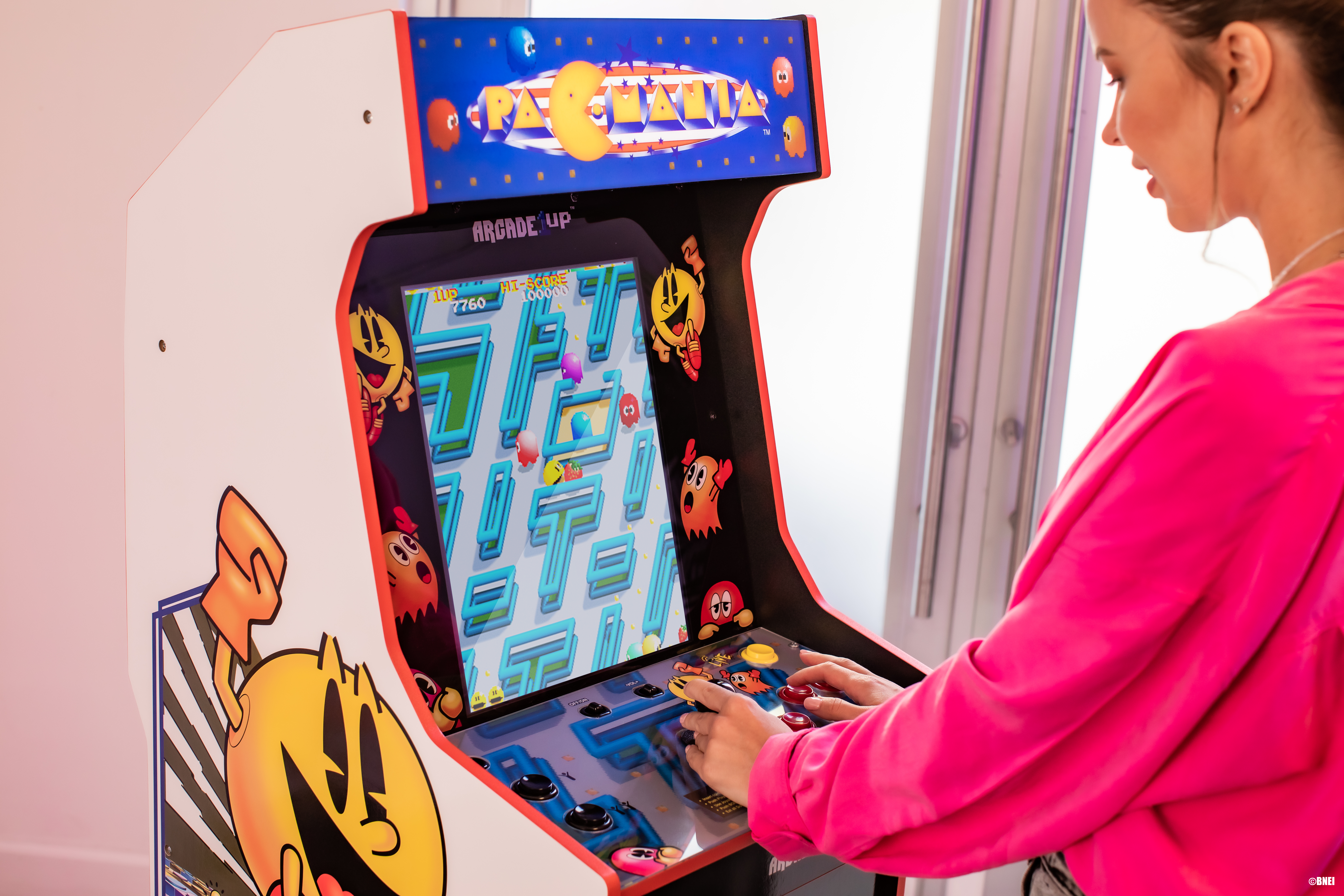 Frau spielt Pac-Man-Arcade-Spiel, rechte Seitenansicht.