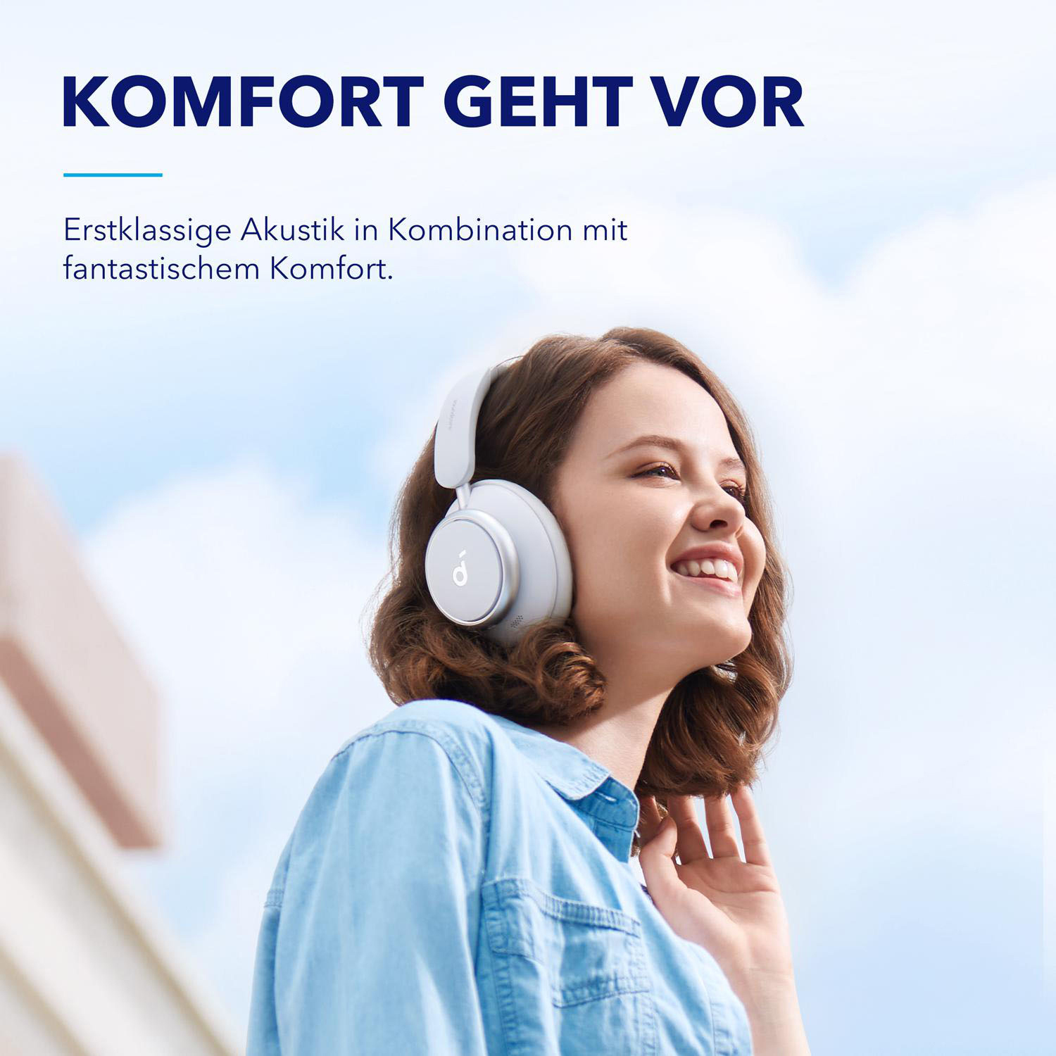 Frau mit weißen Kopfhörern lächelt. Himmel im Hintergrund.