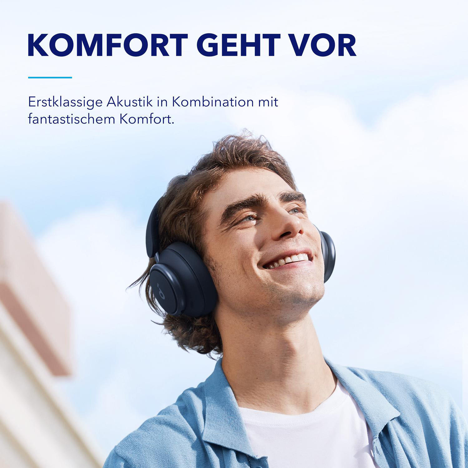 Ein Mann in blauem Hemd mit Kopfhörern, lächelt in die Kamera.