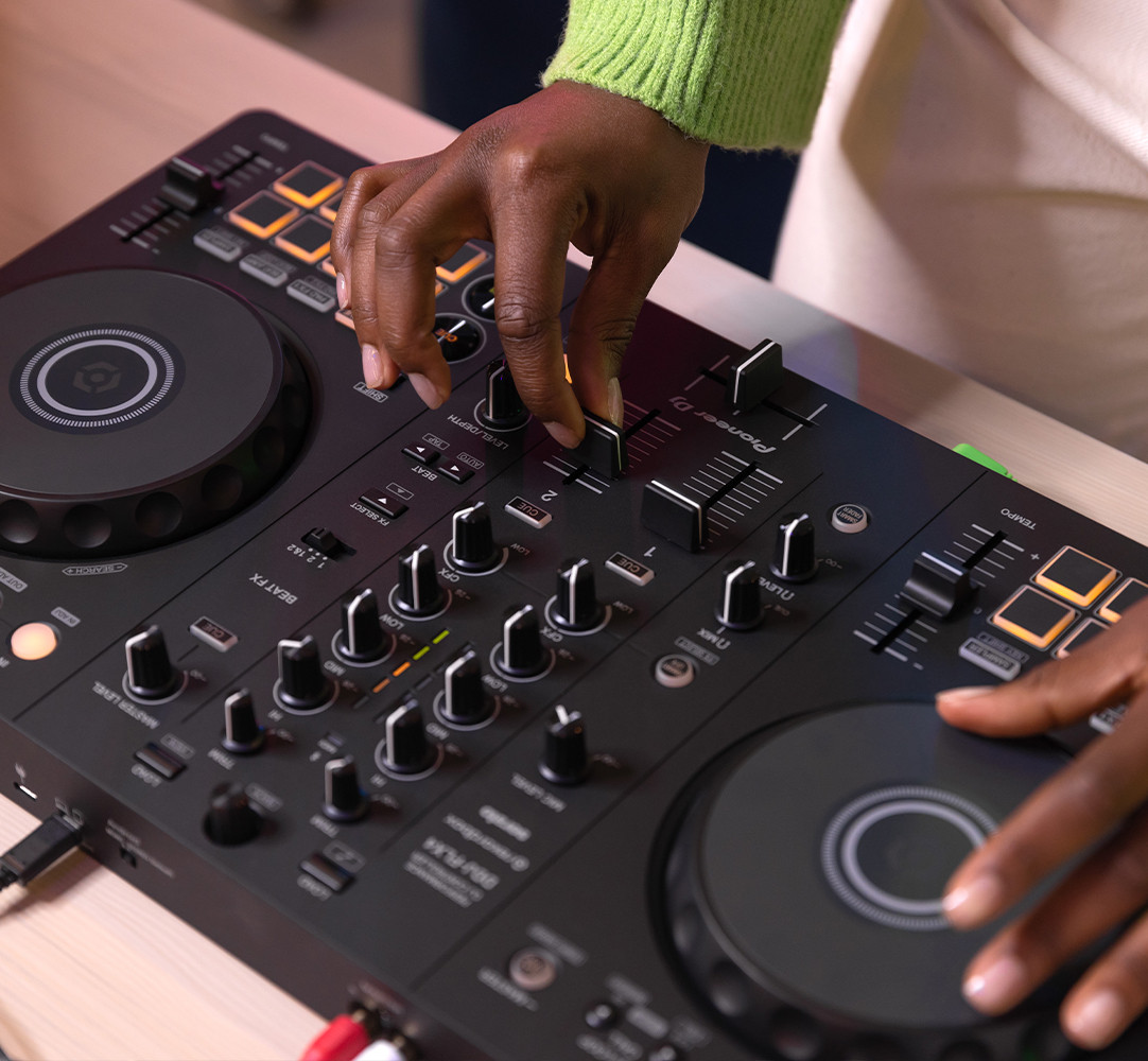 A person's hands operating a DJ mixer with various knobs and buttons visible.