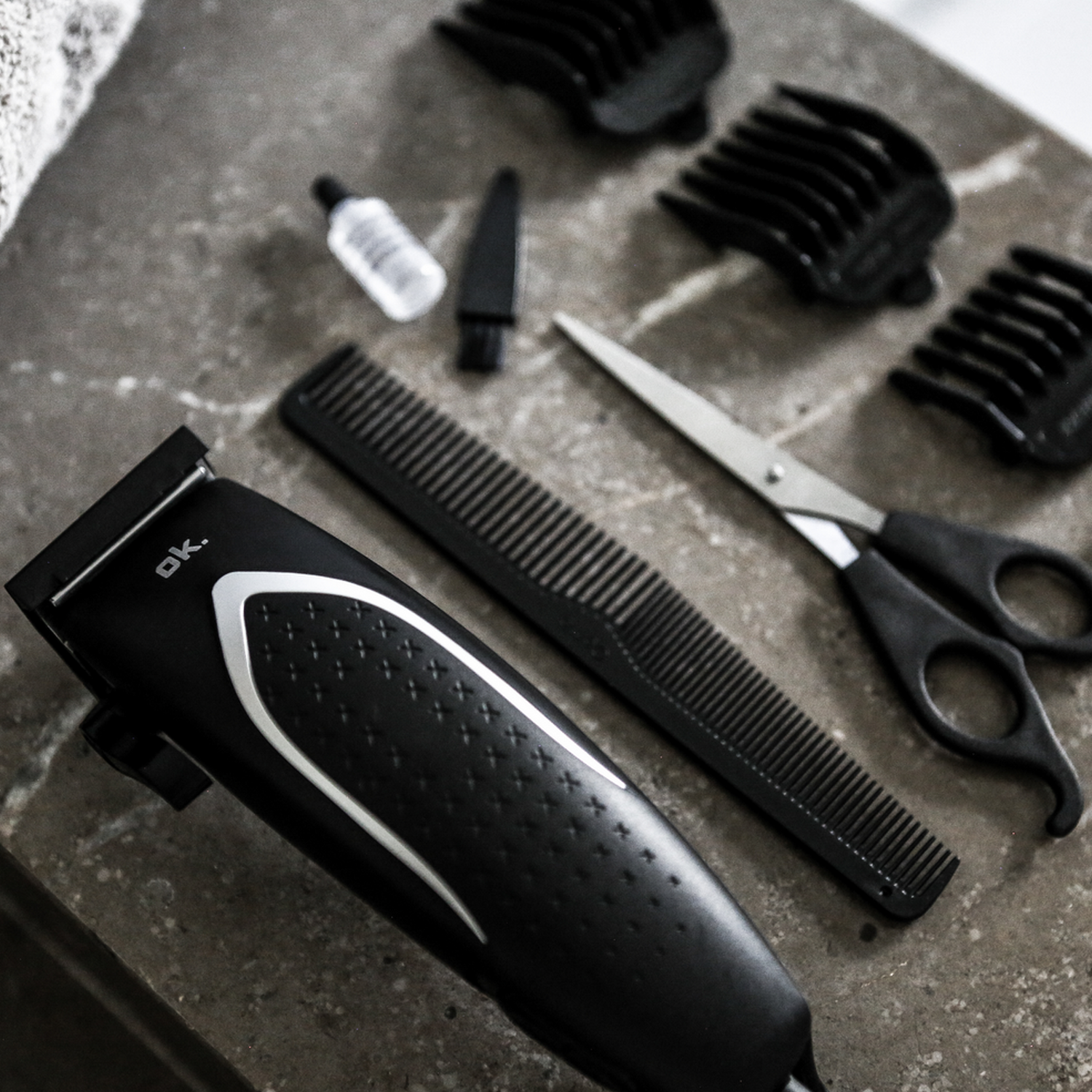 Grooming tools on a stone surface. Includes clippers, scissors, and comb.