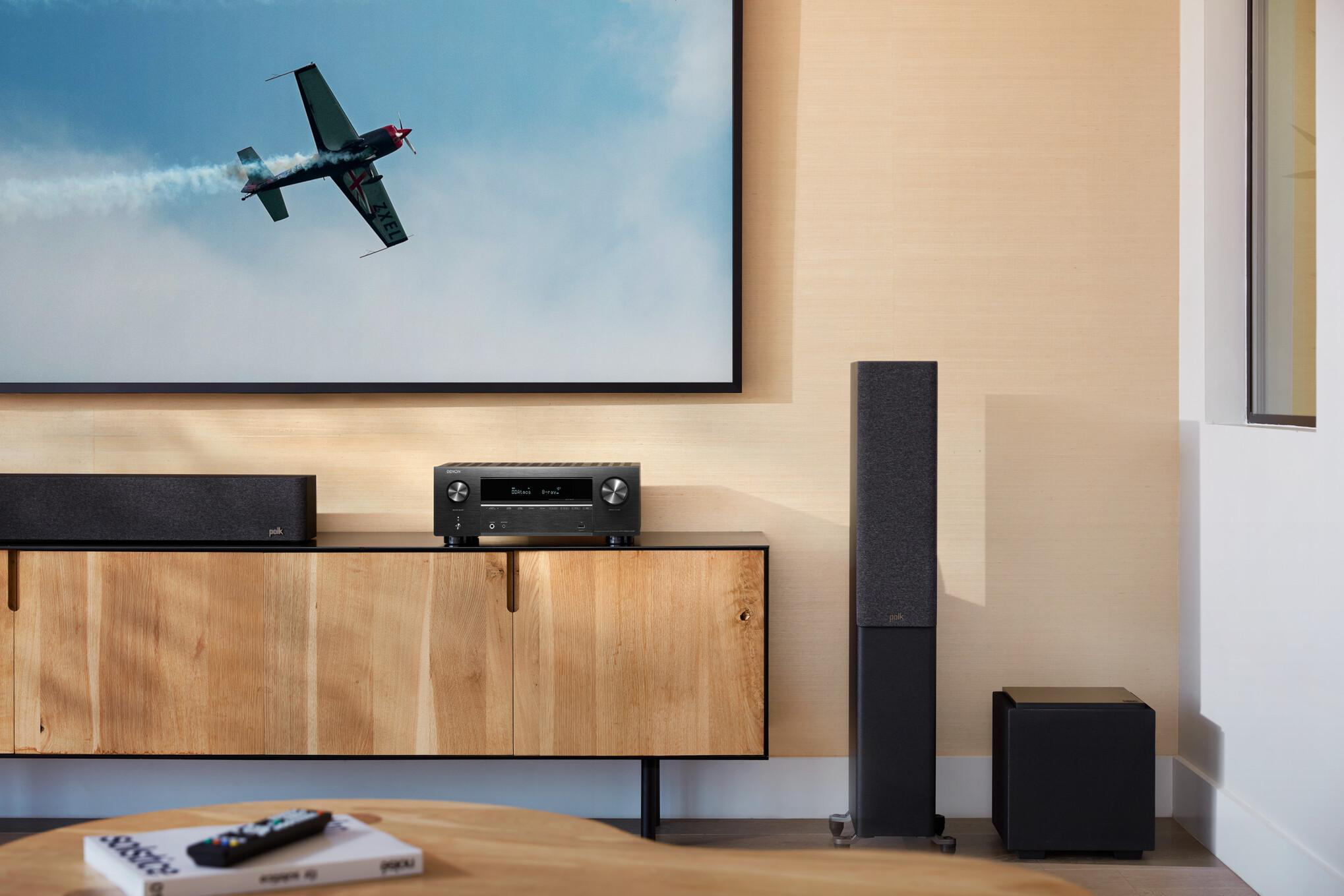 Wohnzimmer mit Fernseher und Soundsystem, einschließlich Soundbar, Receiver und Lautsprecher.