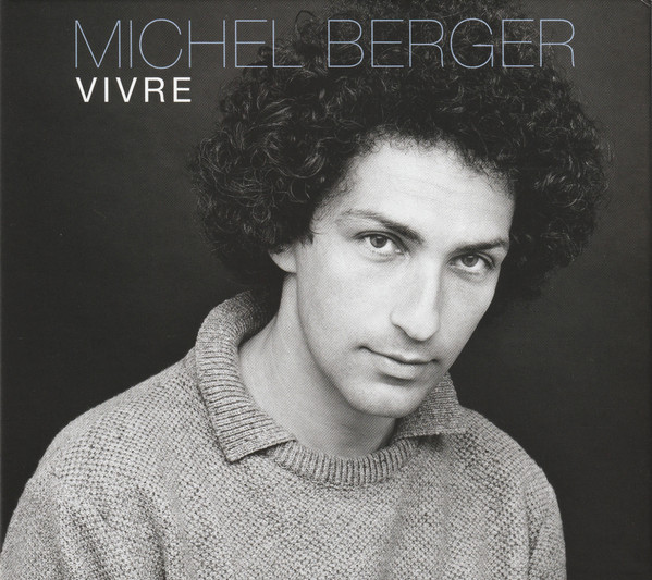 Photo en noir et blanc de Michel Berger, cheveux bouclés, portant un pull.