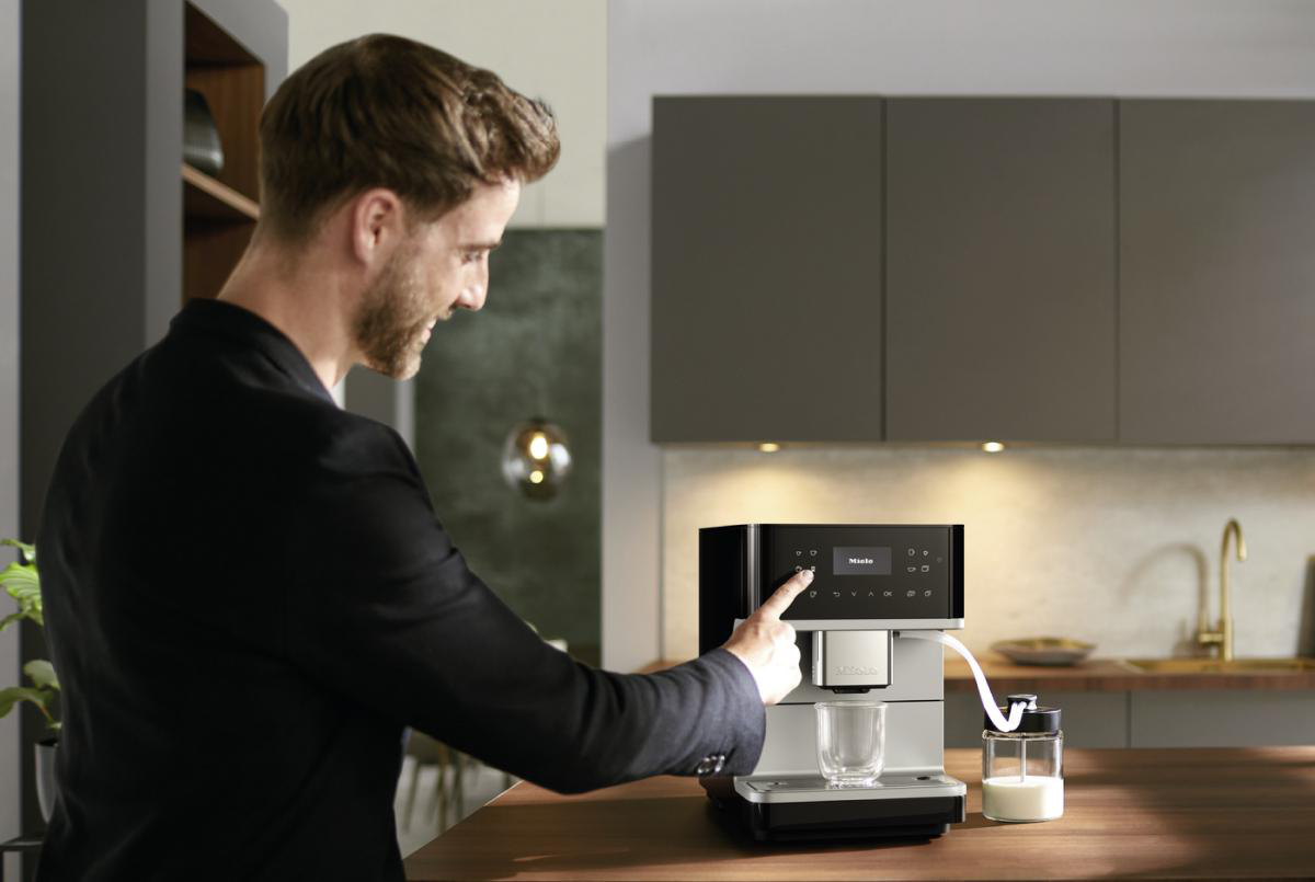 Ein Mann bedient eine Kaffeemaschine und gießt Kaffee in ein Glas.