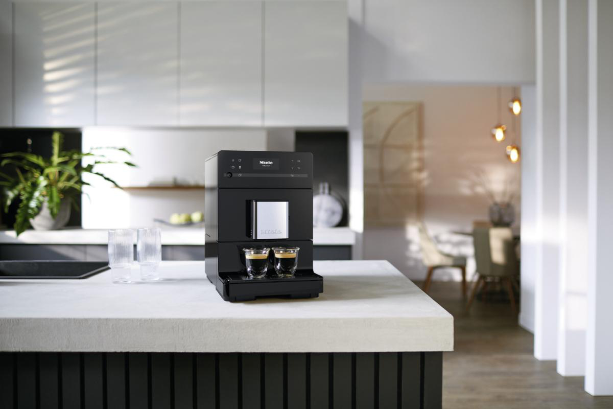 Eine schwarze Espressomaschine auf einer Arbeitsplatte in einer modernen Küche.
