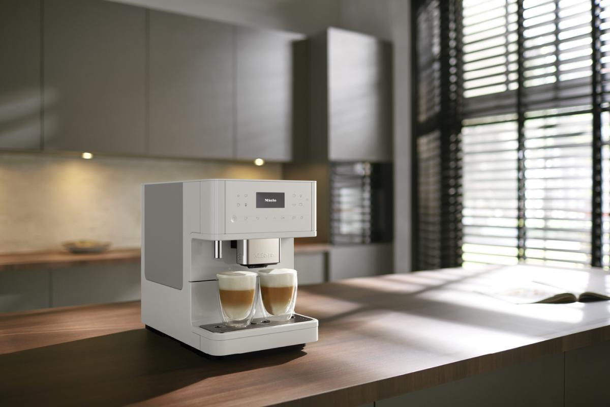 Weiße Miele Kaffeemaschine auf einer Holztheke.