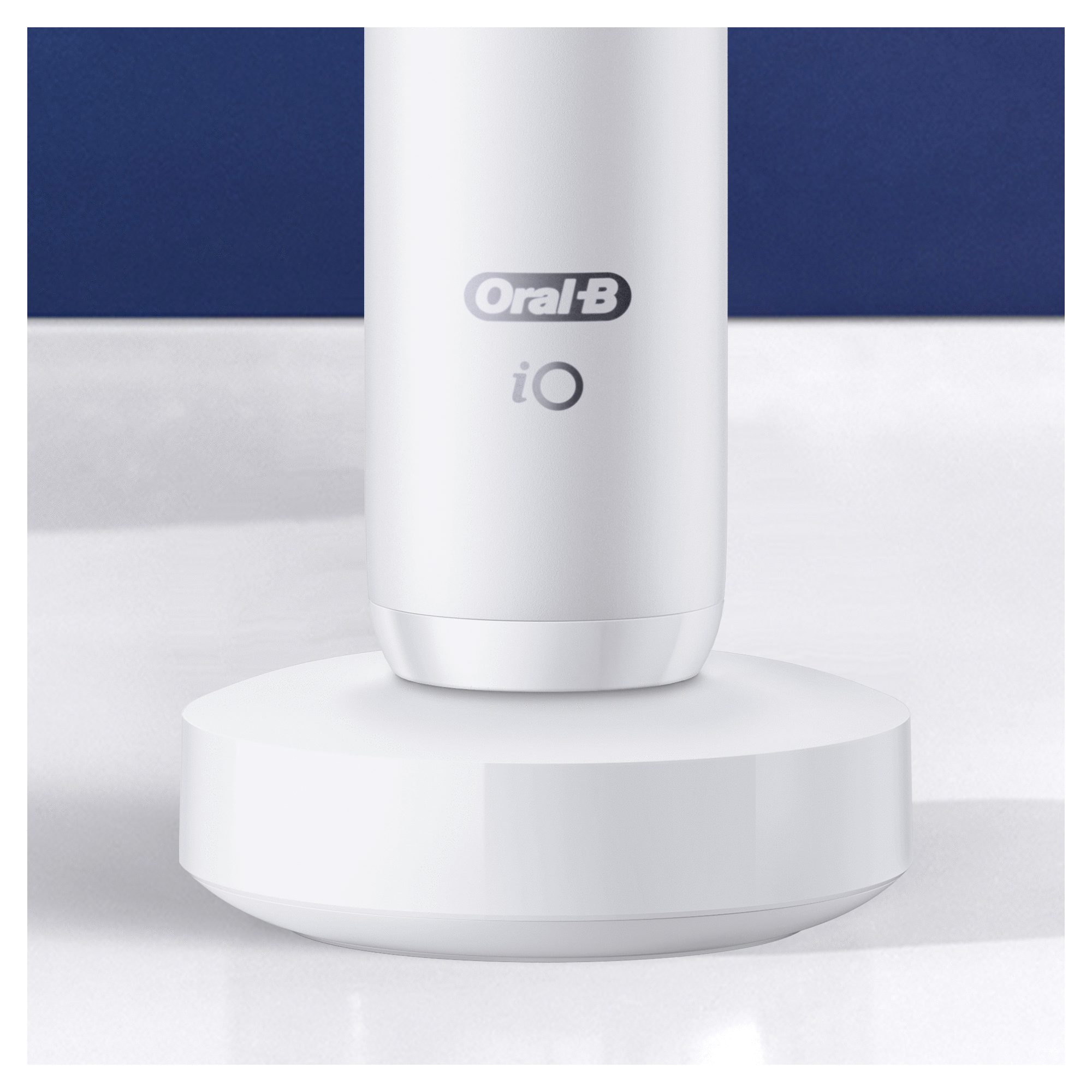 A white Oral-B iO electric toothbrush on its white charging base.