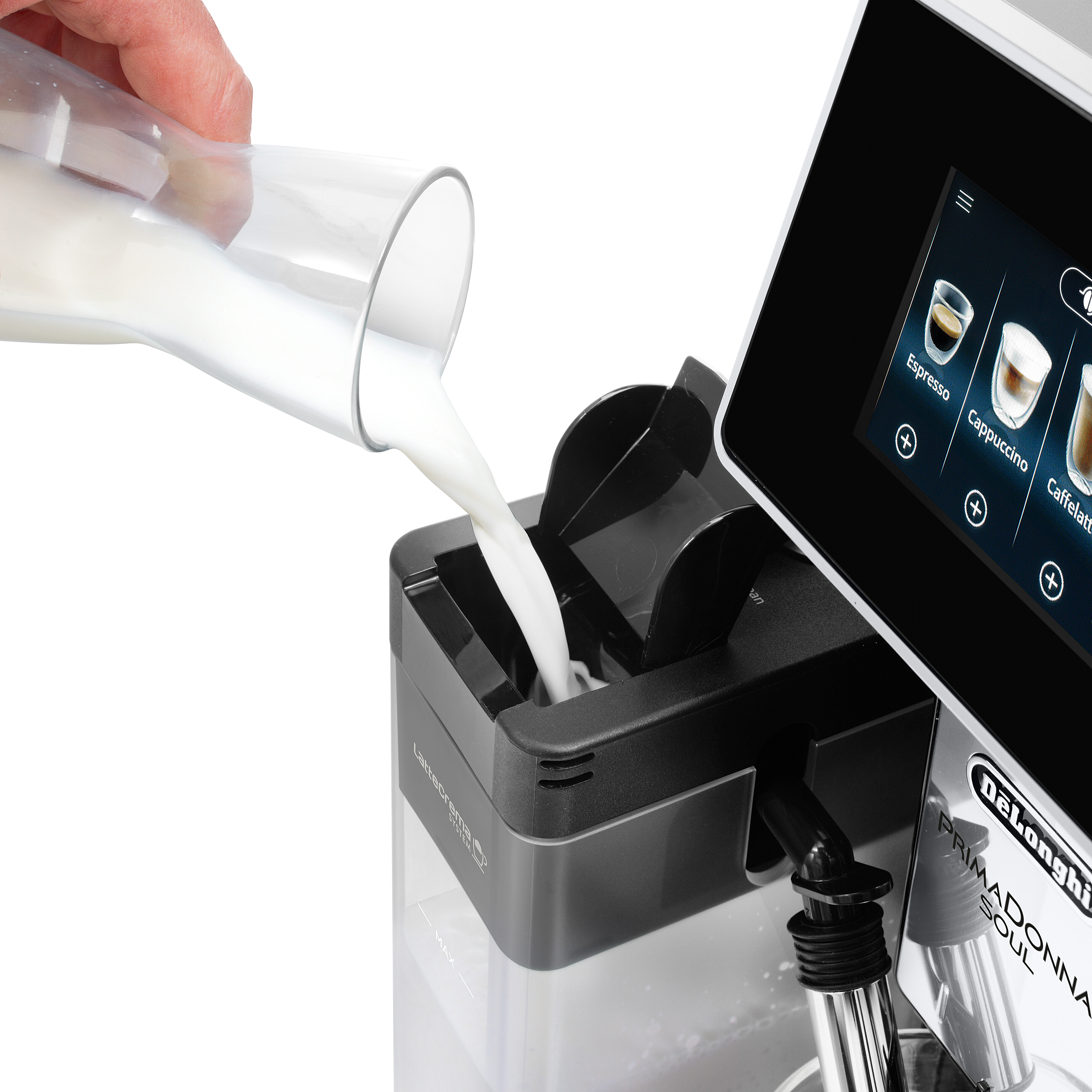 Eine Hand gießt Milch aus einem Glaskrug in den Milchbehälter einer Kaffeemaschine. Weißer Hintergrund.