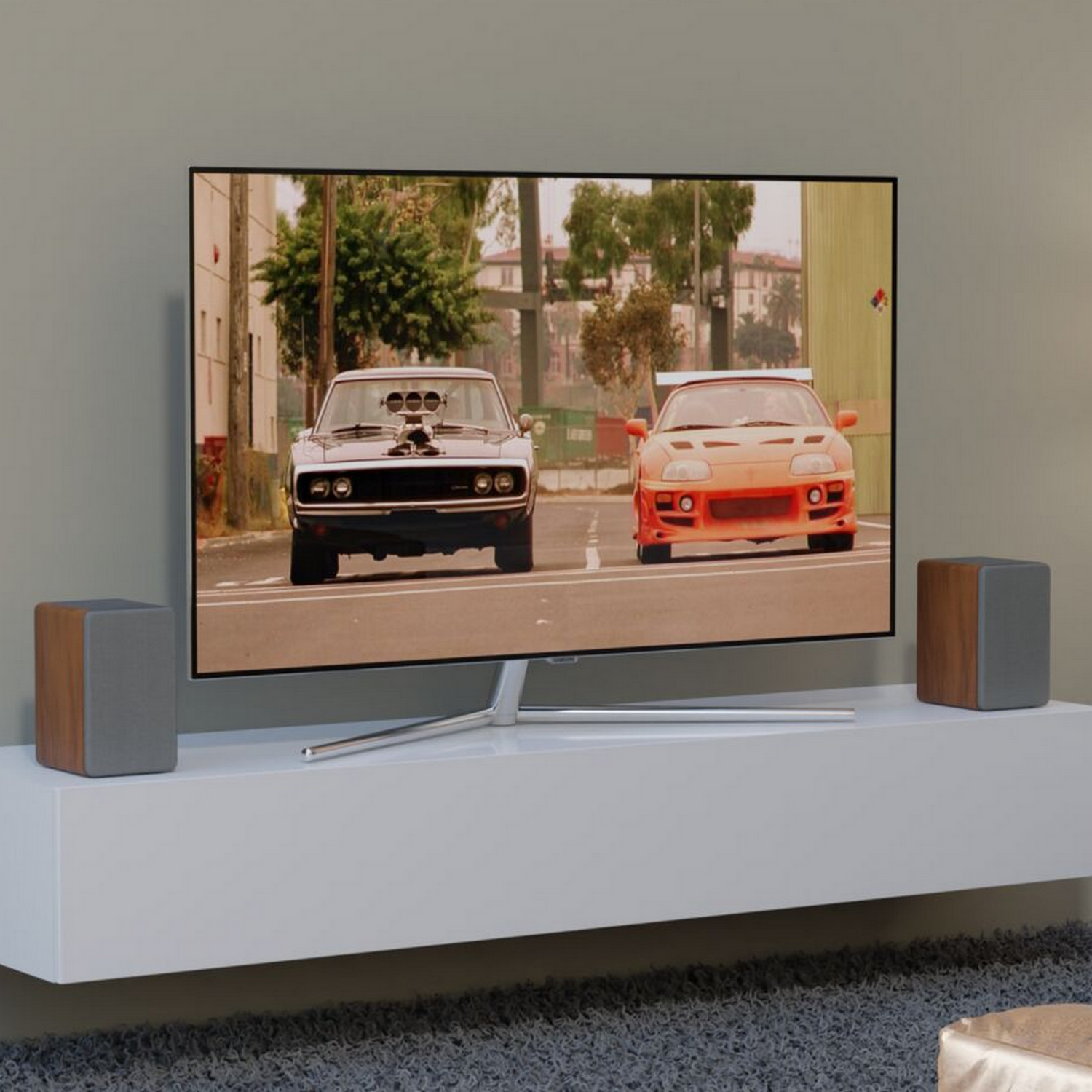 A TV showing a scene with two cars racing. Speakers are on each side of the TV.