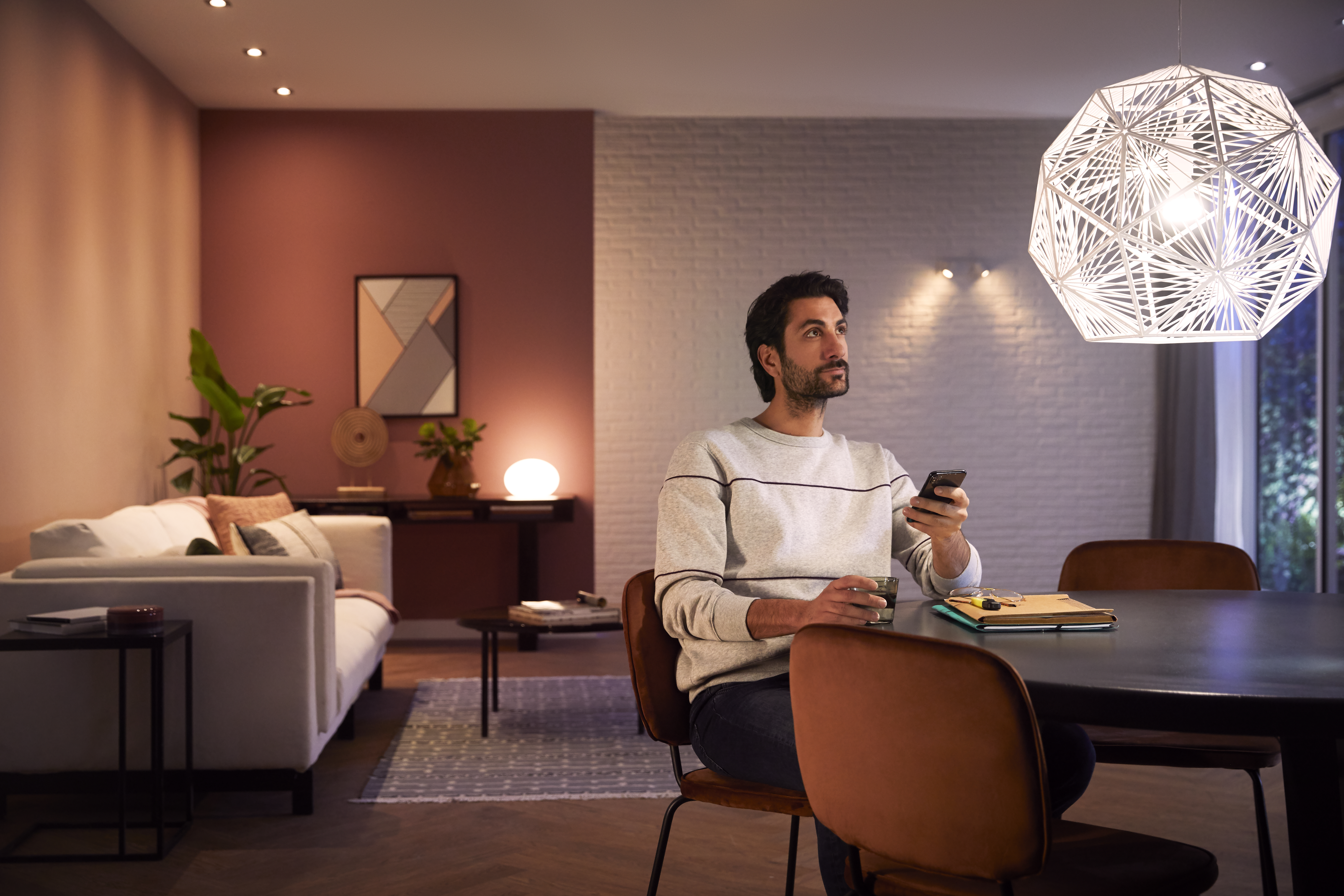 Mann im Wohnzimmer mit Telefon, der nach oben schaut.