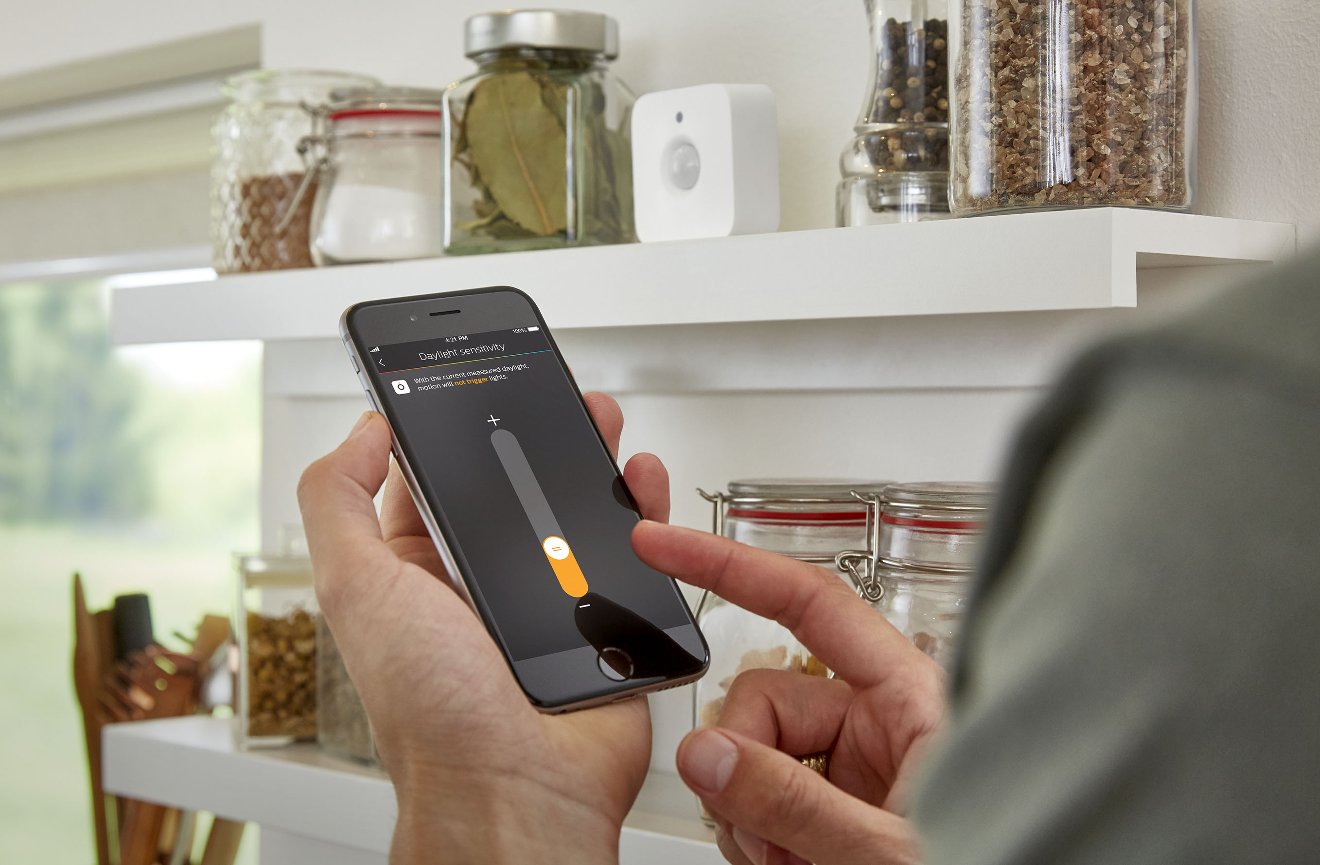 Person interagiert mit einem Smartphone, das Smart-Home-Steuerungen anzeigt.