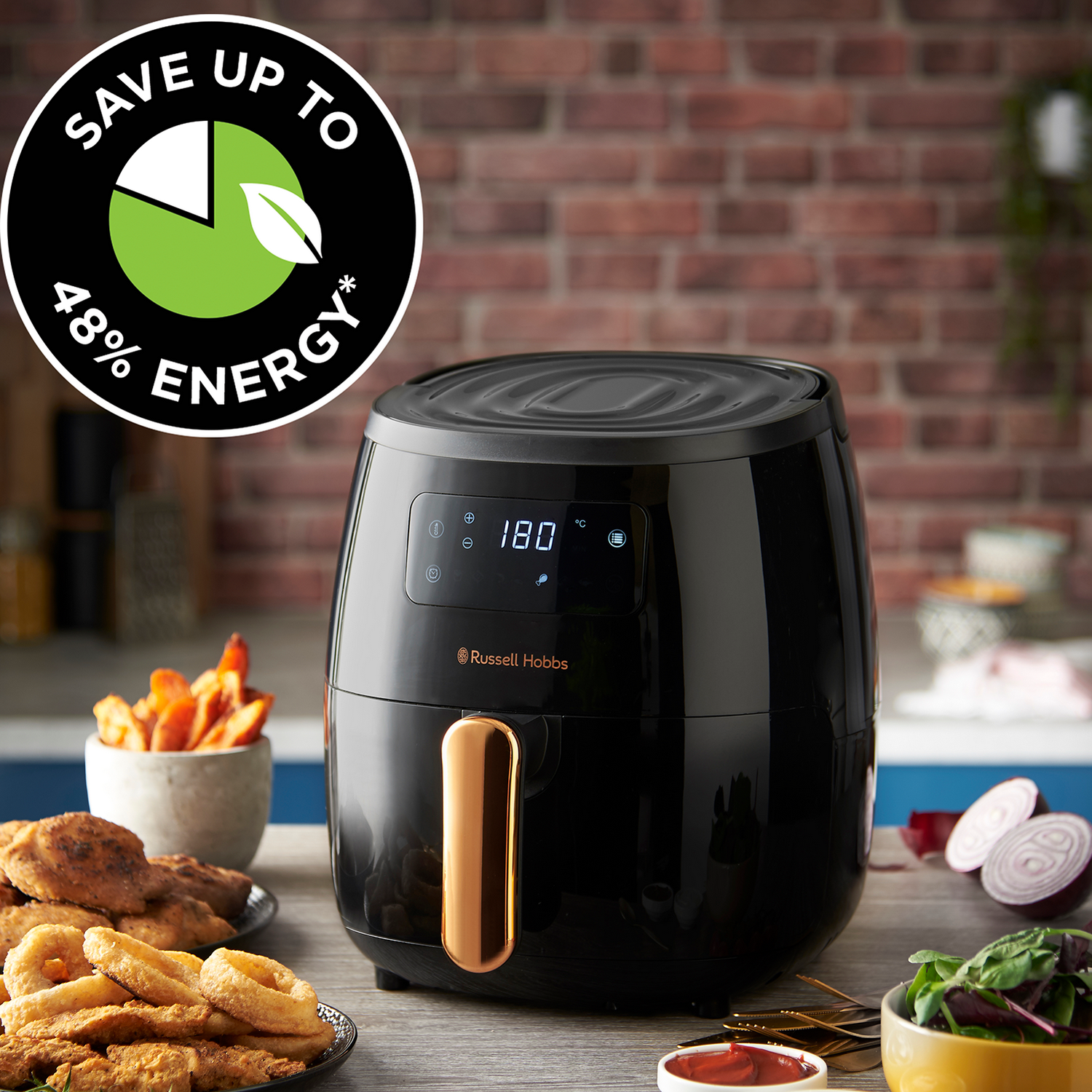 Zwarte airfryer met een gouden handvat, omringd door eten op een tafel. De tekst luidt 'Bespaar tot 48% energie'.
