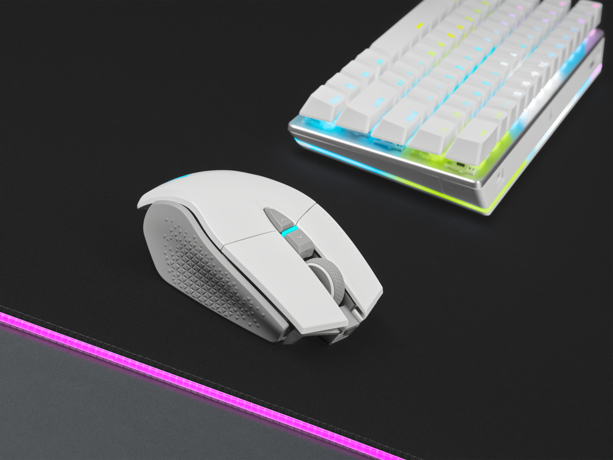 Weiße kabellose Maus mit grauem Scrollrad und Tastatur auf einem schwarzen Mauspad.