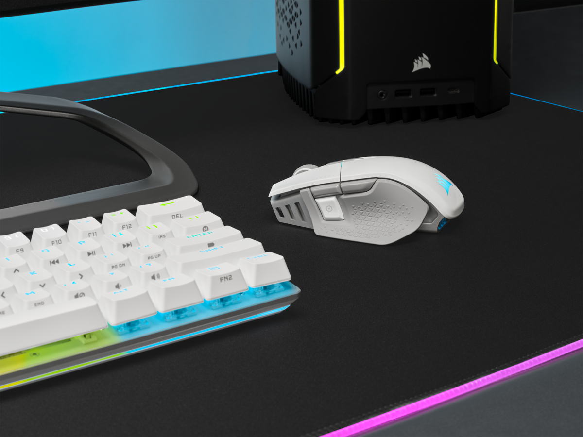Weißes Maus- und Tastatur-Setup auf einem schwarzen Mauspadd, mit einem schwarzen Computer.