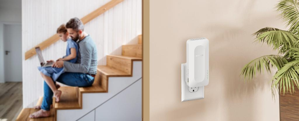 Vater und Kind mit Laptop, WLAN-Verlängerer an der Wand.