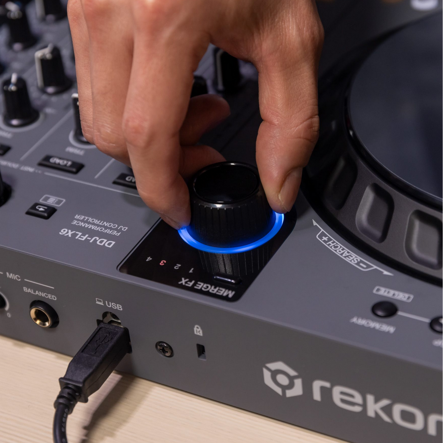 Een hand stelt een knop in op een DJ-controller. De knop heeft een blauw licht.