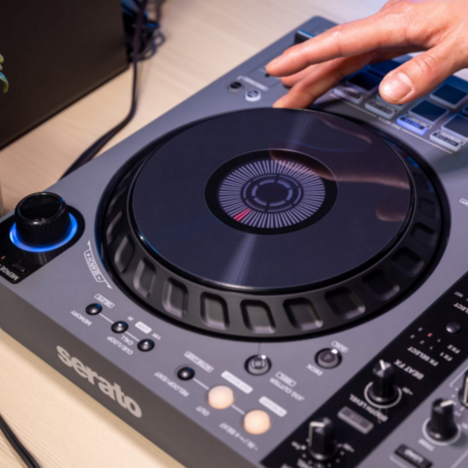DJ-controller met een hand op de jogwheel. Grijs en zwart design.