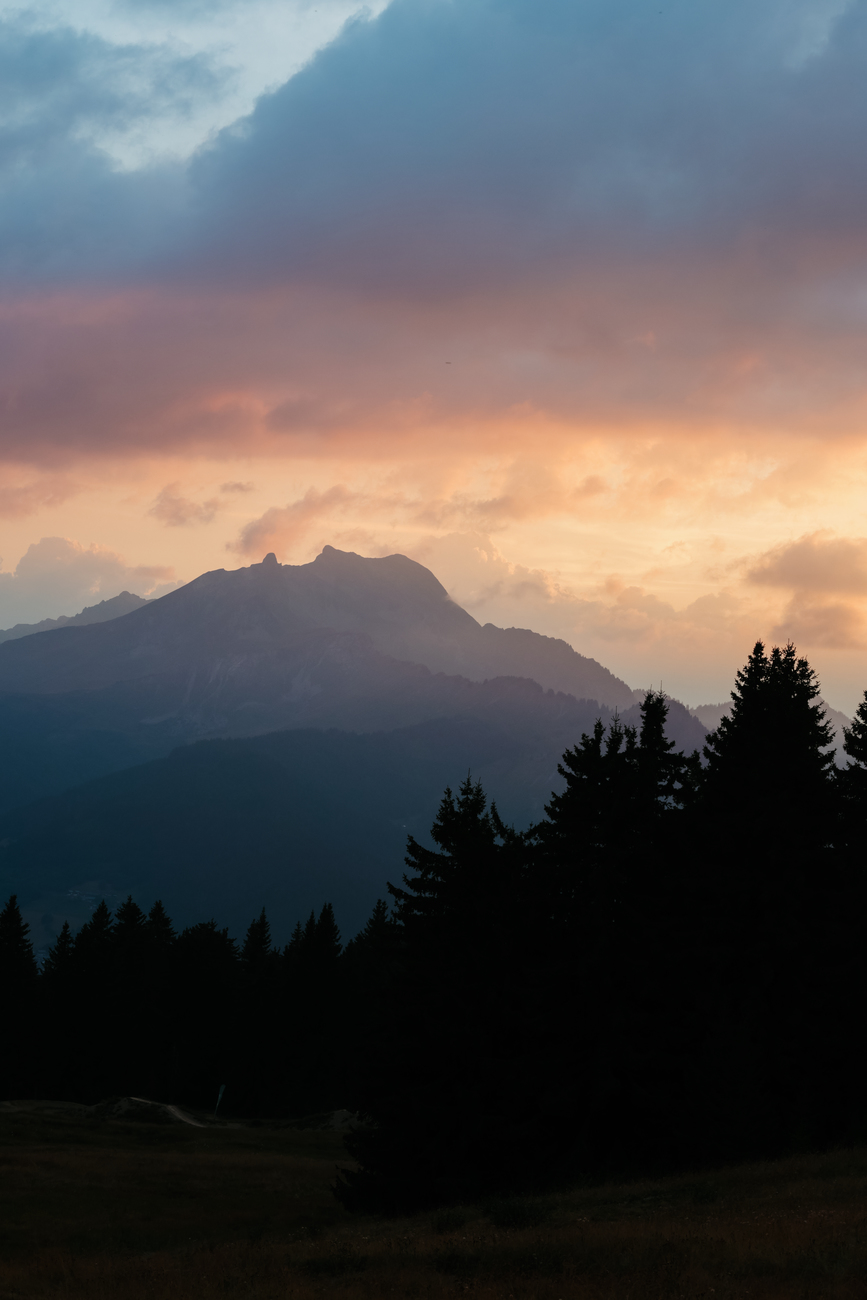 Bergsilhouette vor Sonnenuntergang mit bunten Wolken.